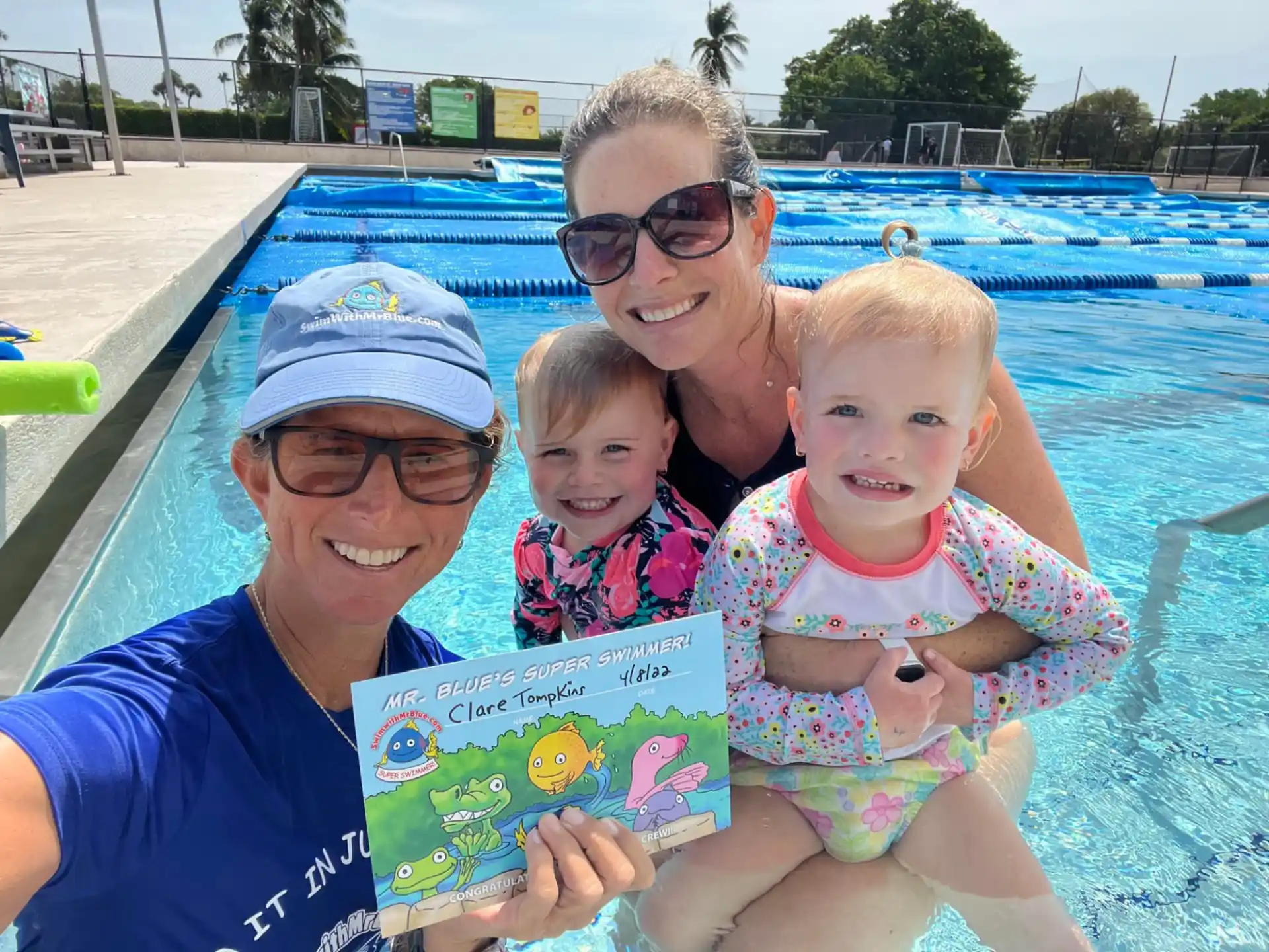 a man and woman holding a couple of children in a pool