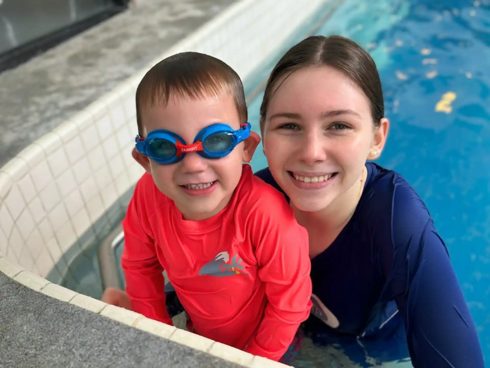 a person and a boy posing for a picture next to a pool