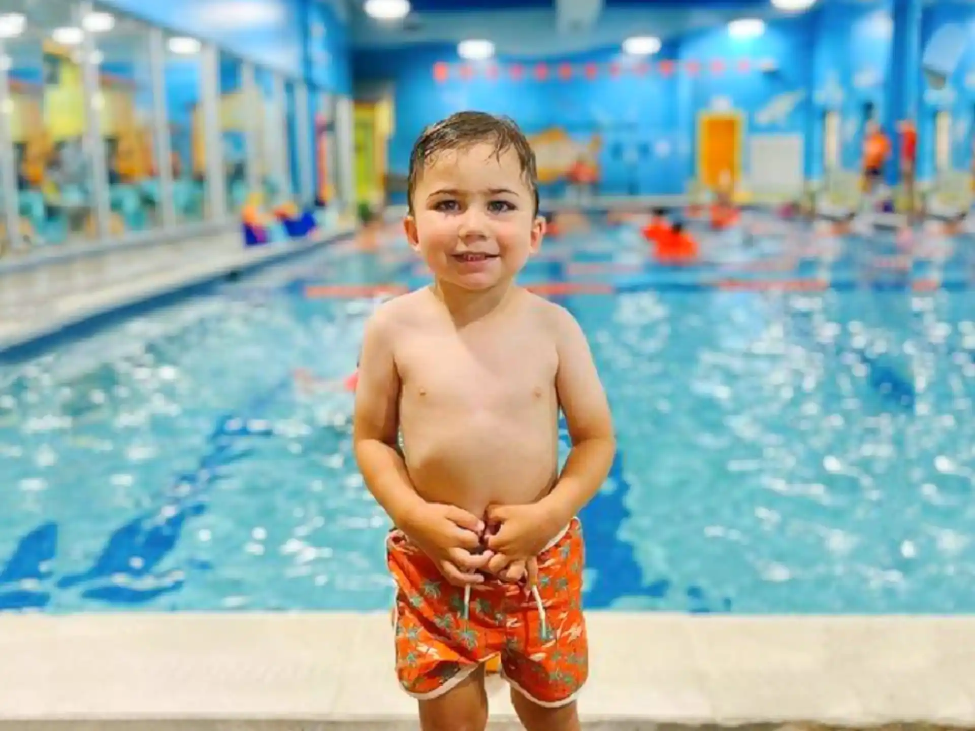 a boy standing by a pool