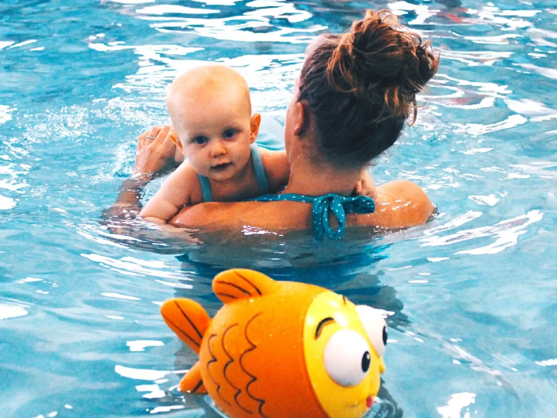 a person and a baby in a pool with a toy in it
