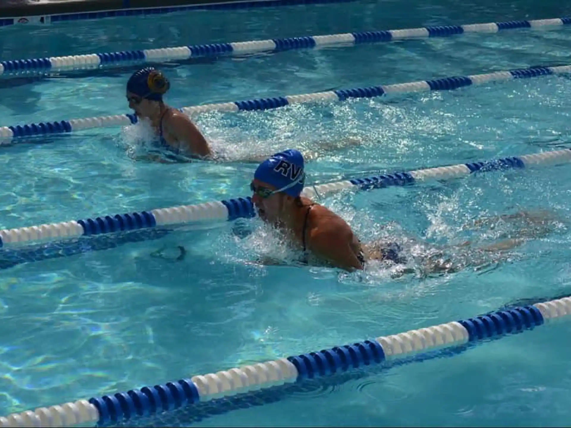 a couple of women swimming in a pool