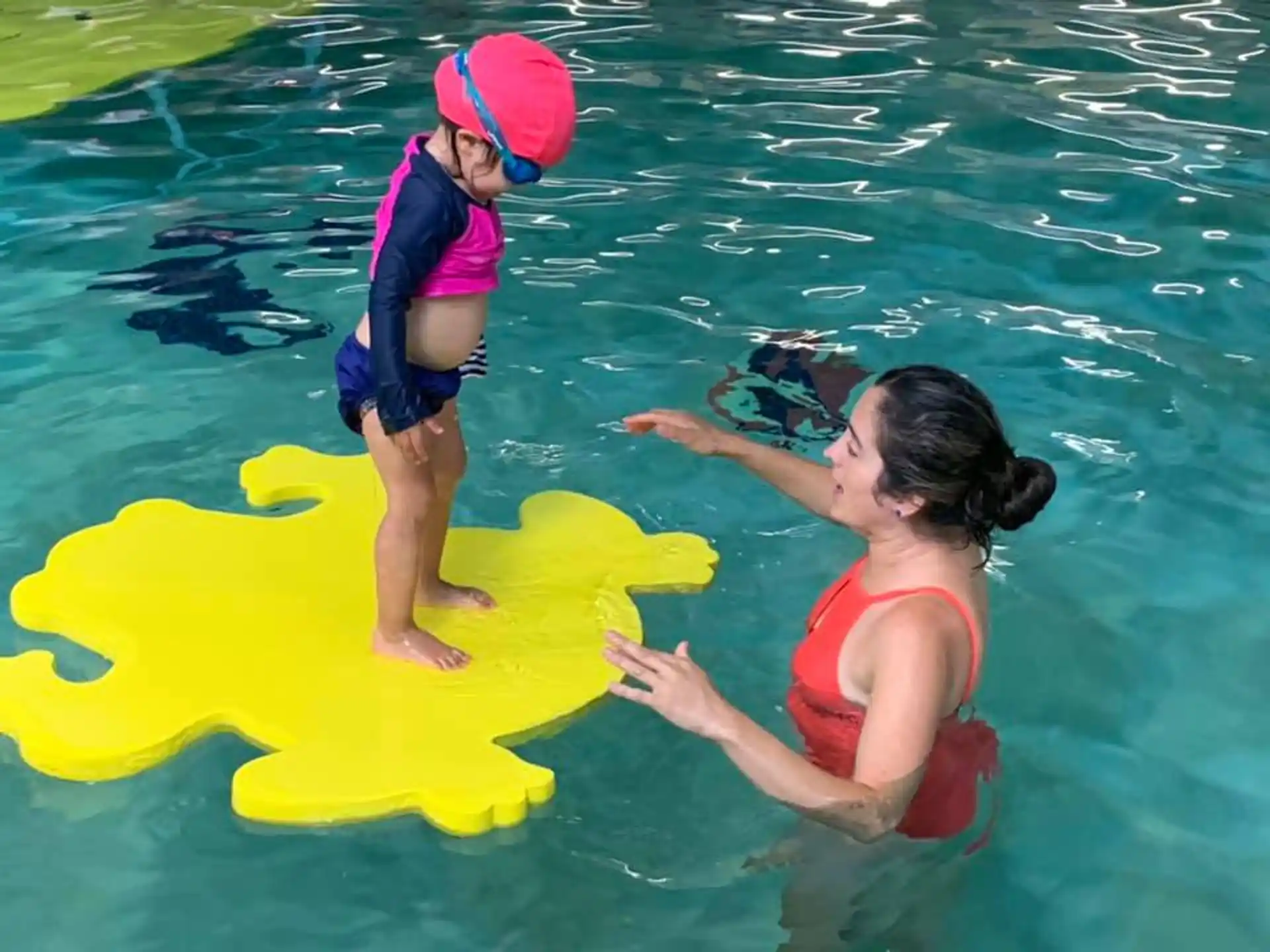 a couple of kids playing in the water with a yellow floaty