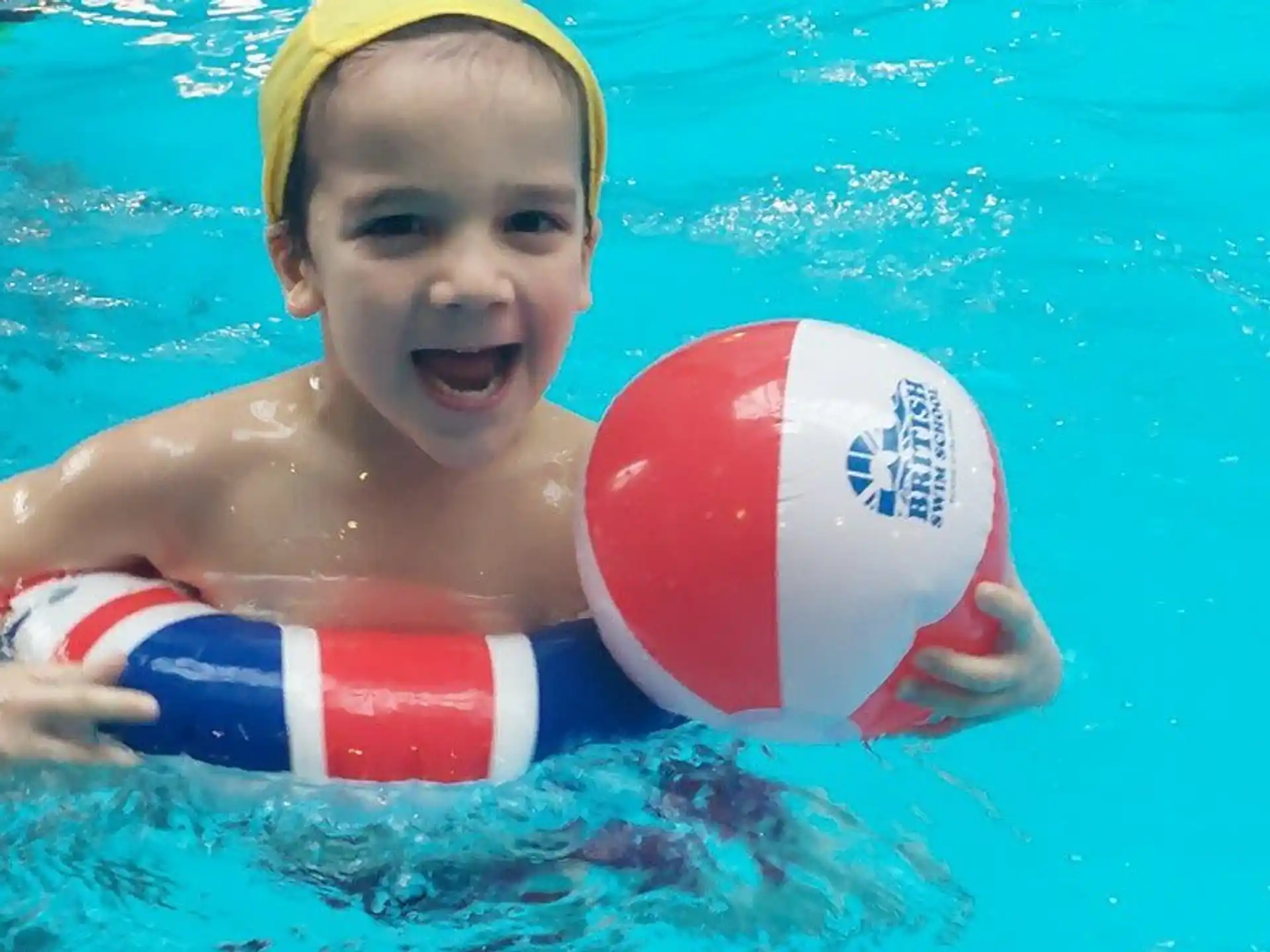 a boy in a pool with a ball