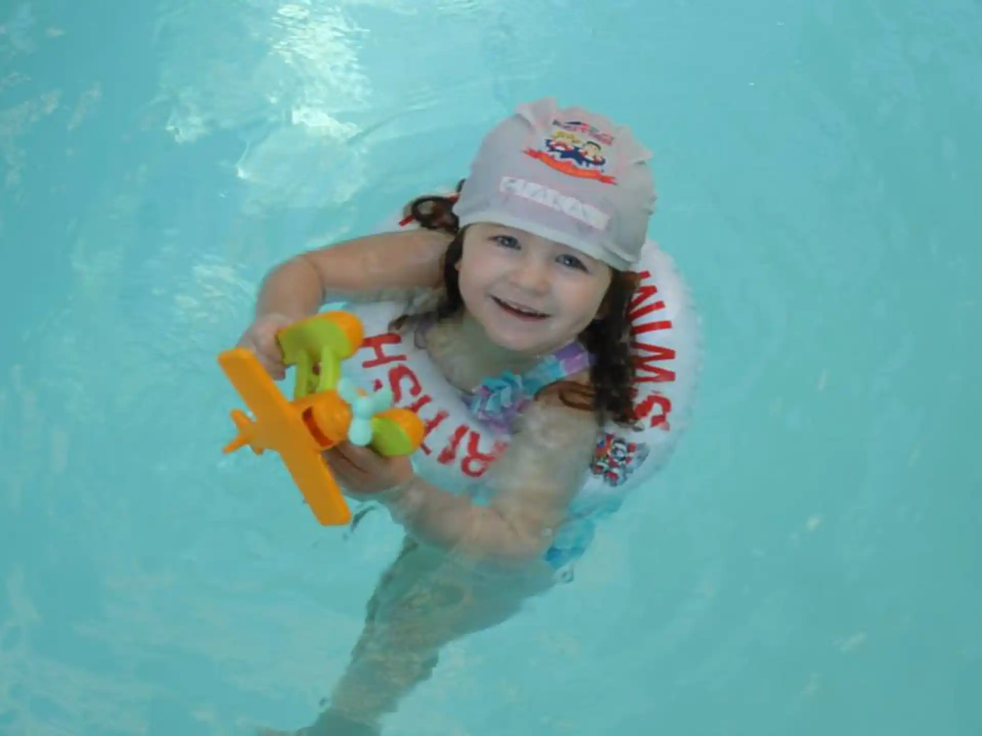 a girl in a pool holding a toy