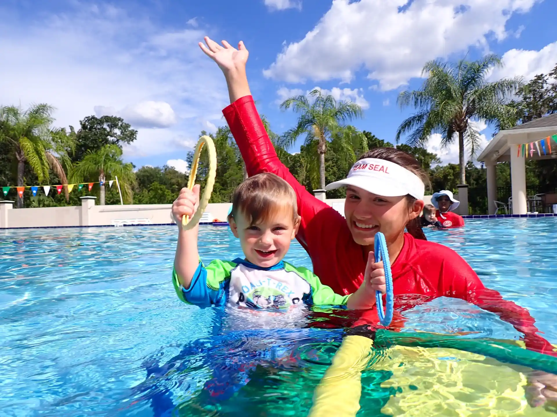 a person and a boy in a pool holding a fish