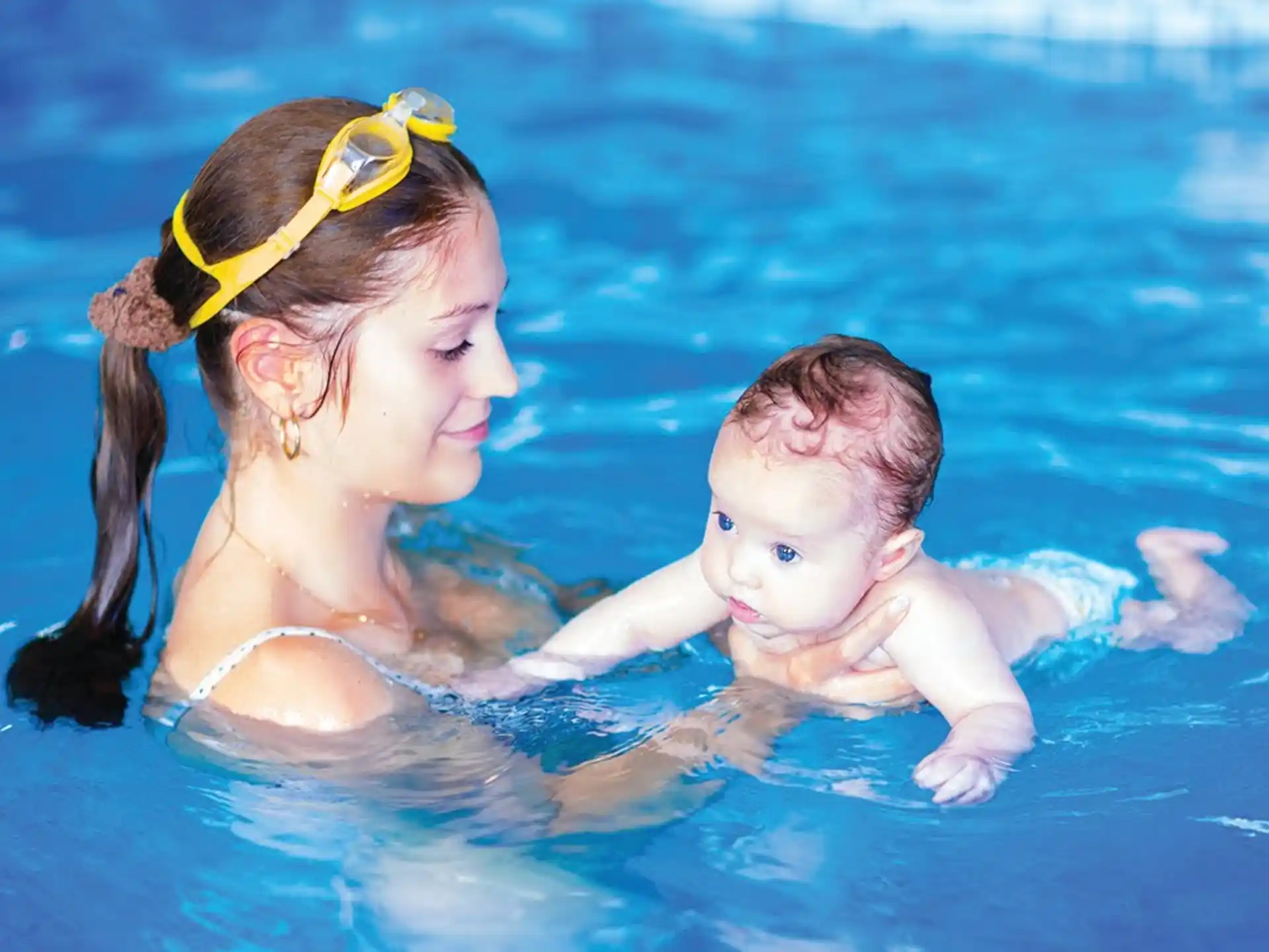 a person holding a baby in a pool