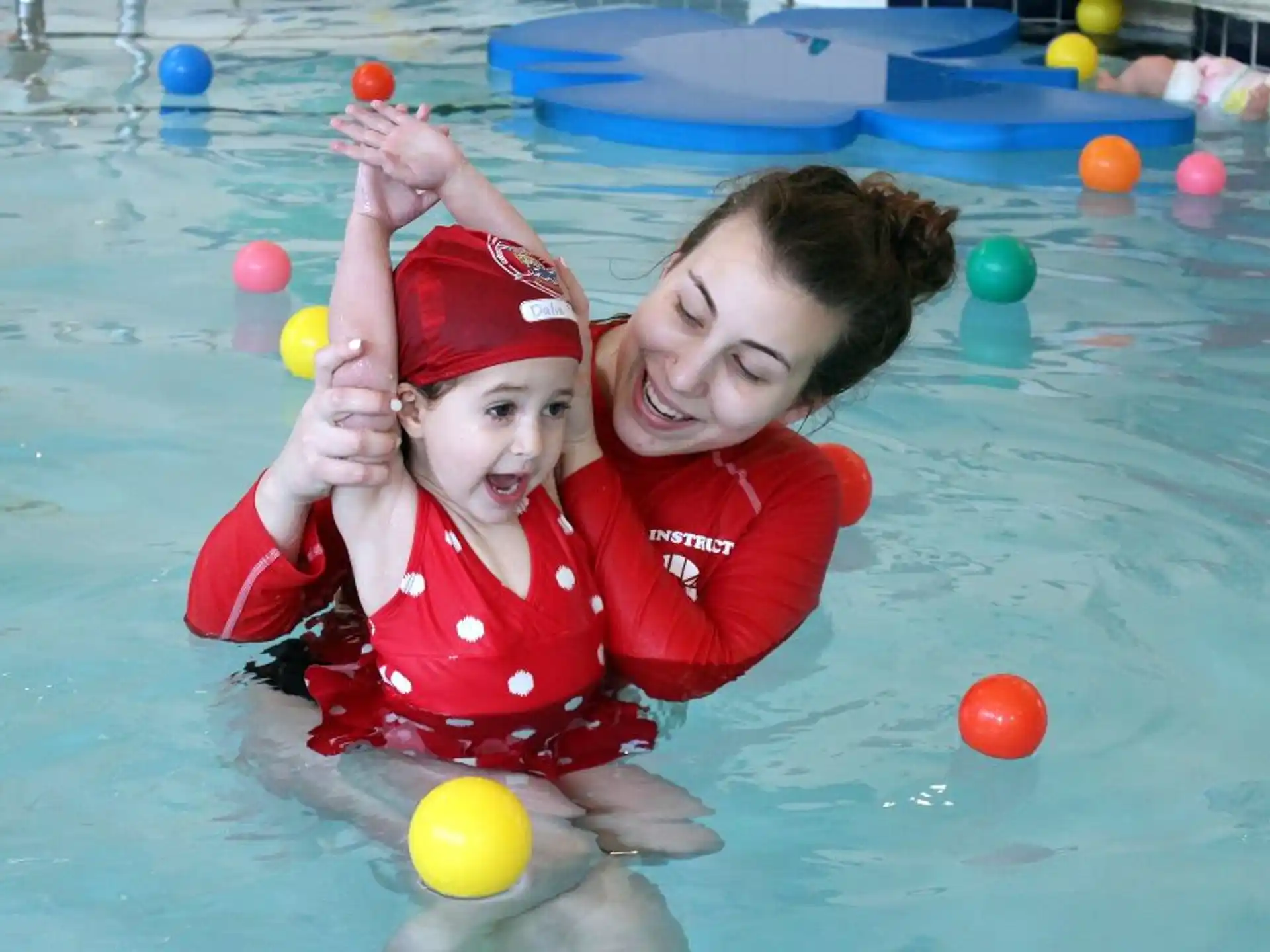 a person and a child in a pool with balls
