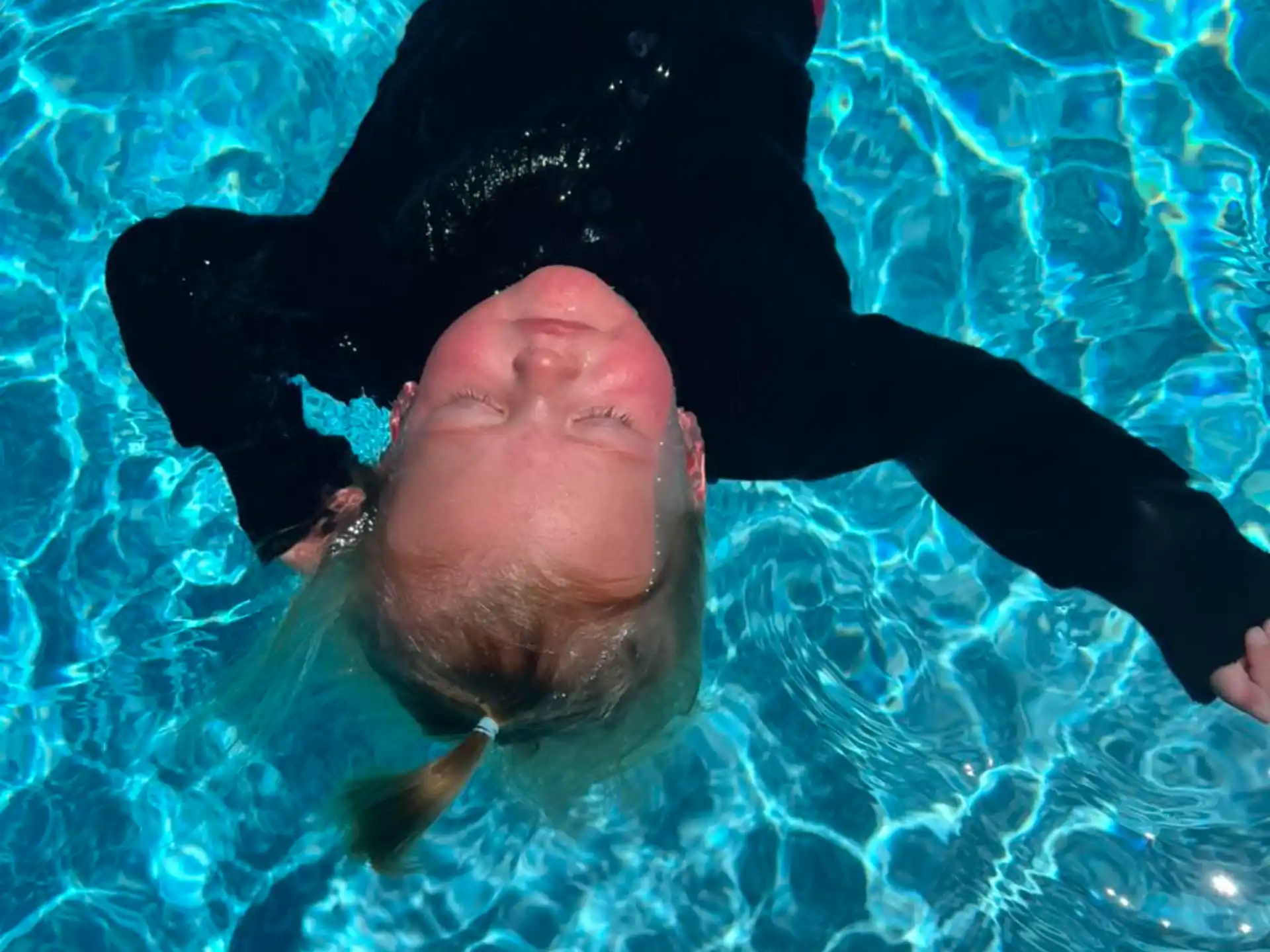 a person in a pool with a fish in the mouth
