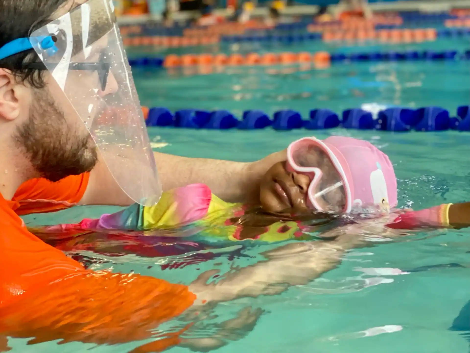 a man in a pool with a dolphin in his mouth