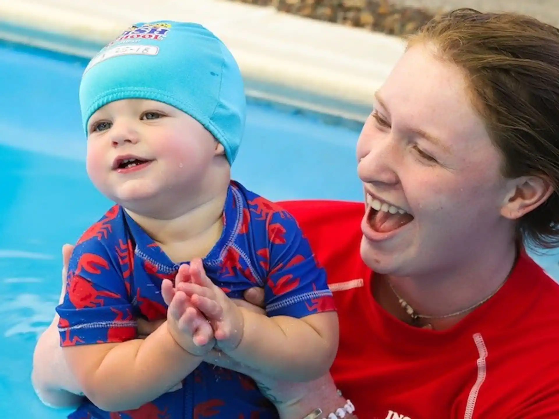 a person holding a baby in a pool