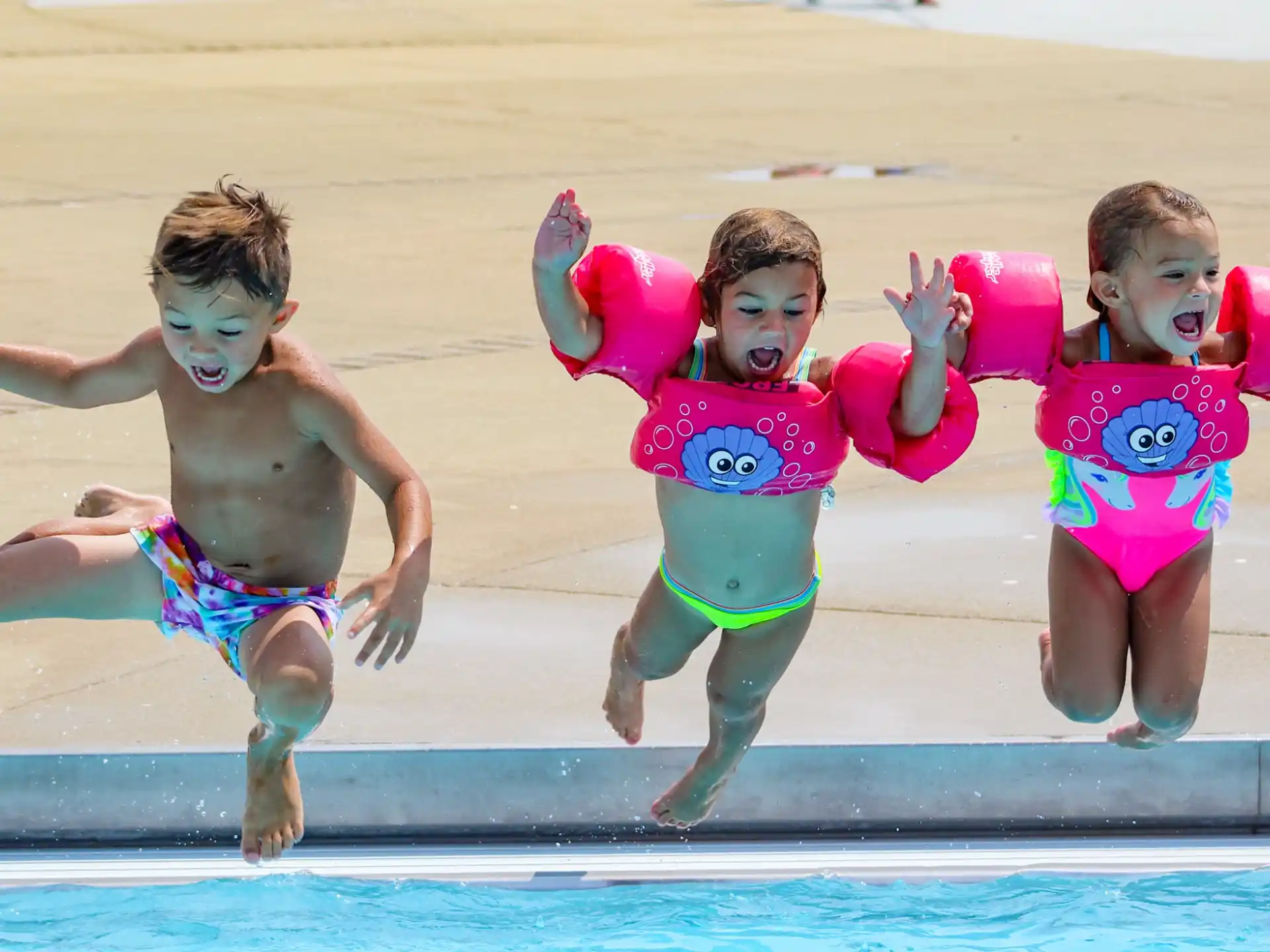 a group of kids jumping into a pool