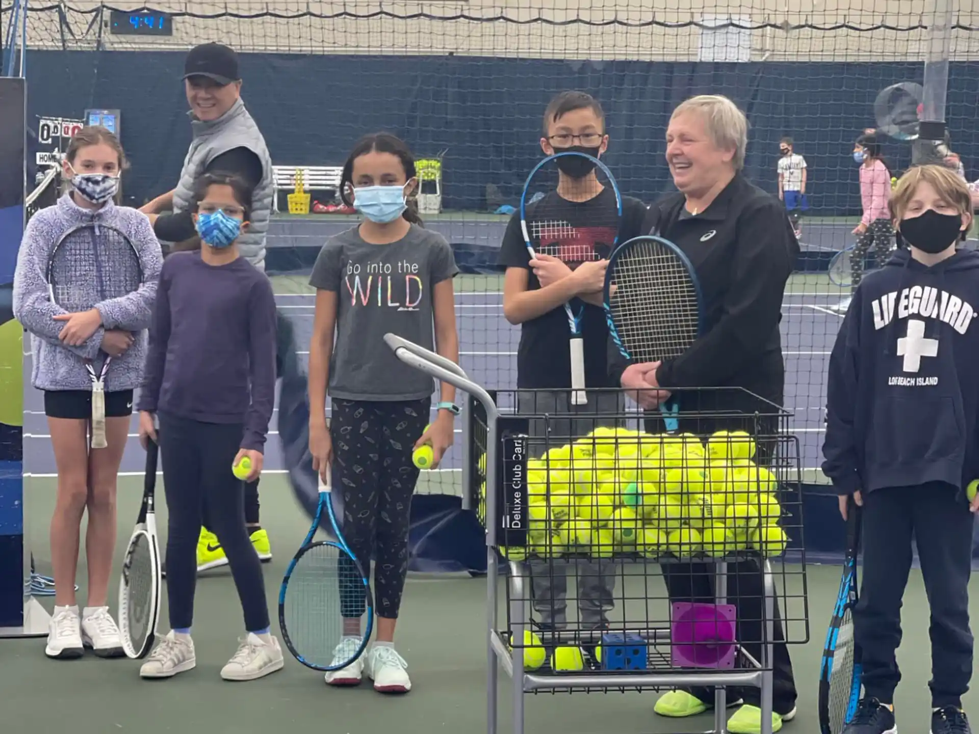 a group of people stand around a tennis cart