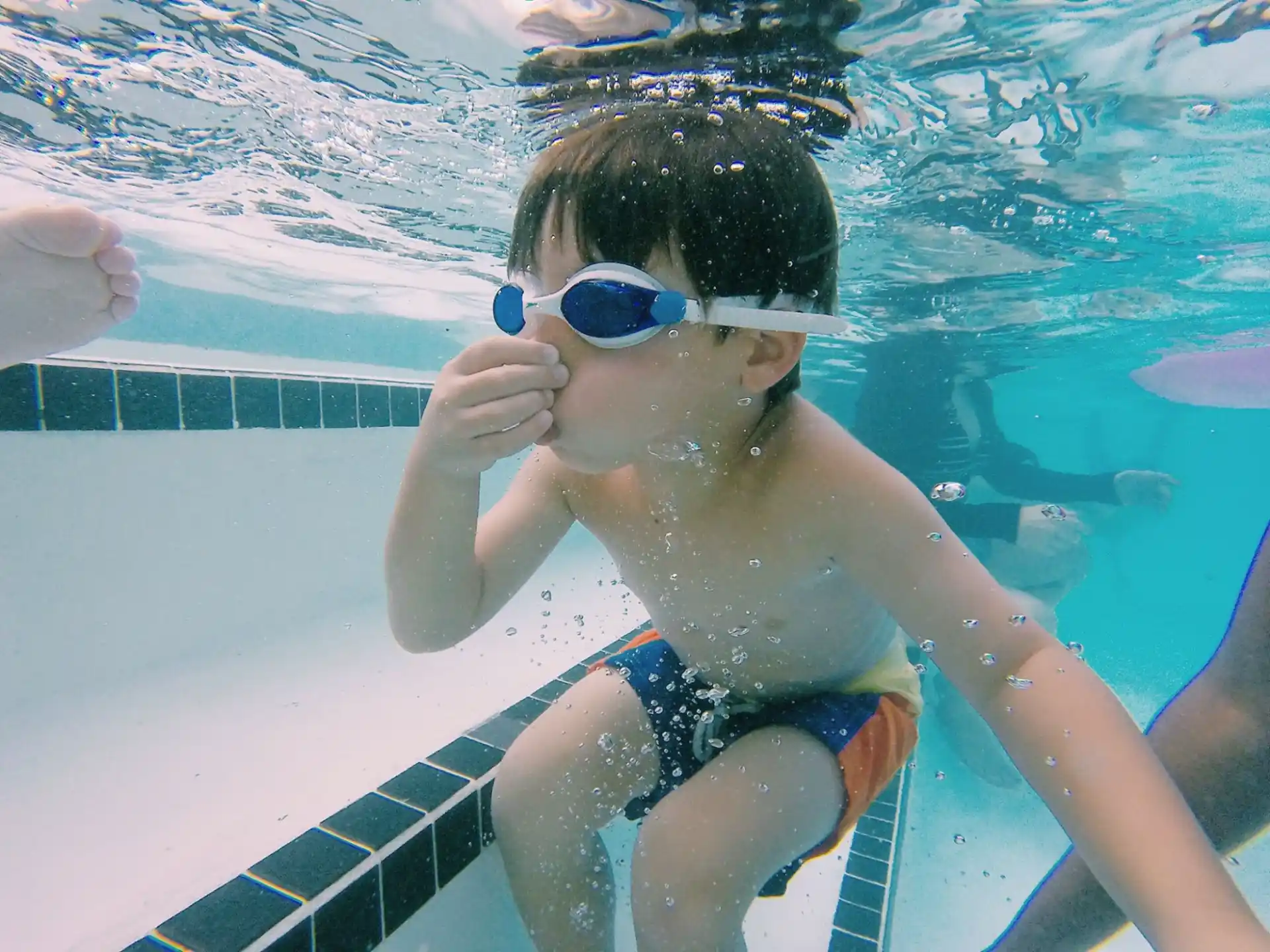 a boy wearing goggles and swimming in a pool