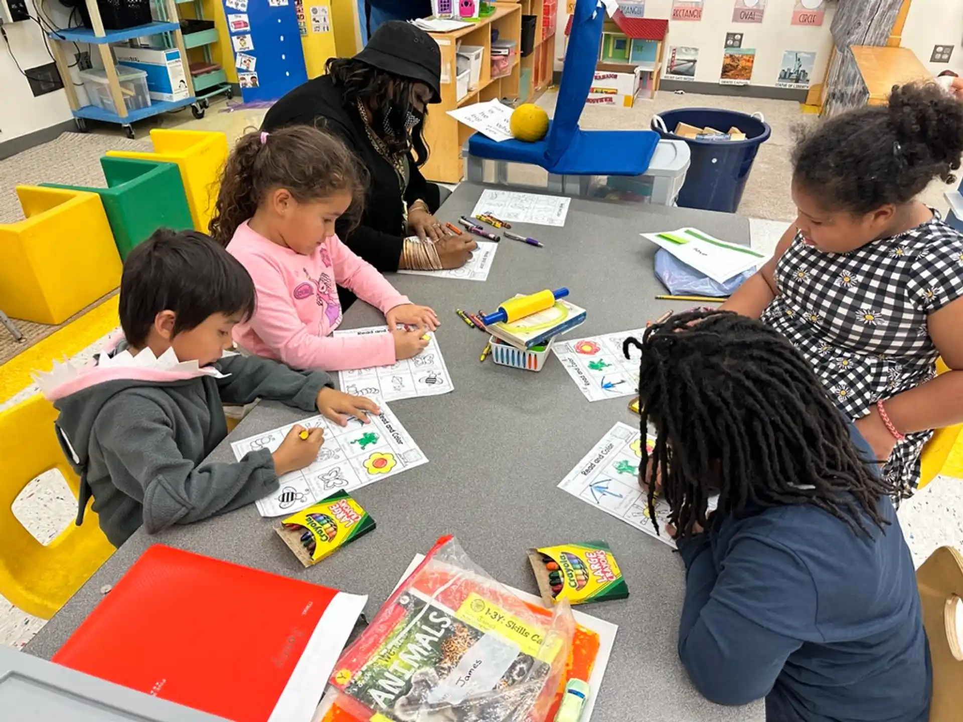 a group of children sitting at a table with books and paper