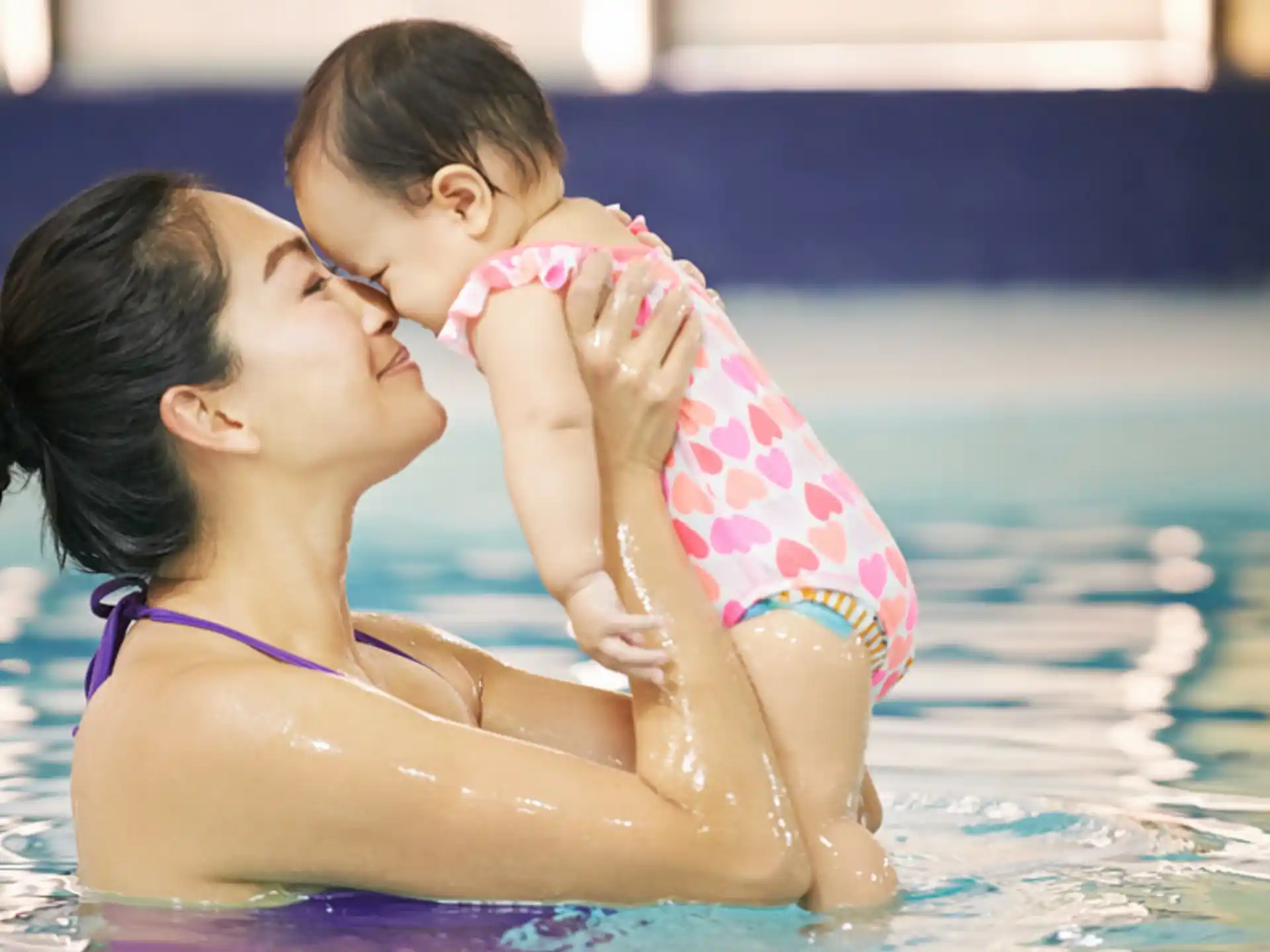 a woman kissing a baby in a pool