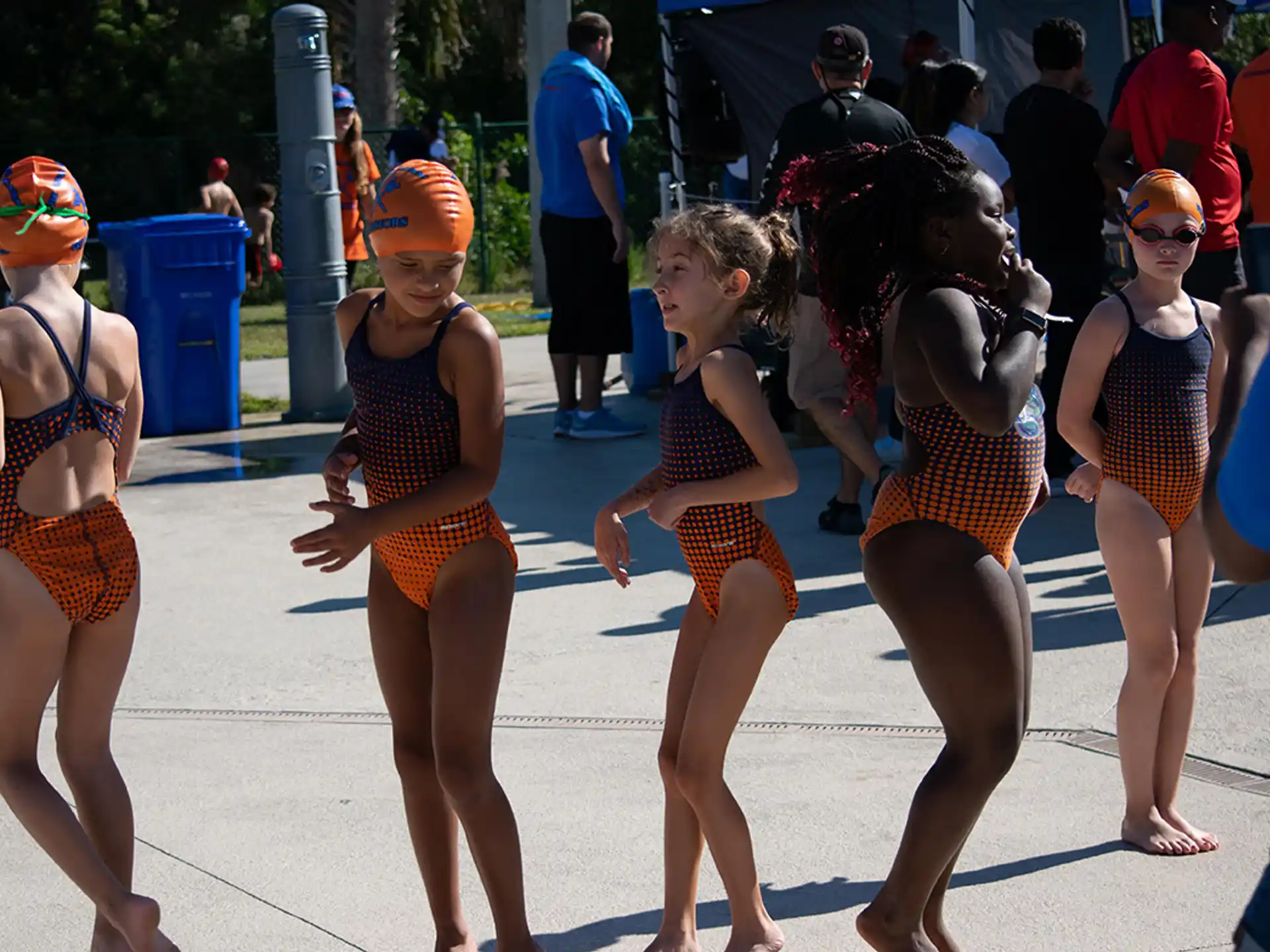 a group of women in swimsuits walking on a sidewalk