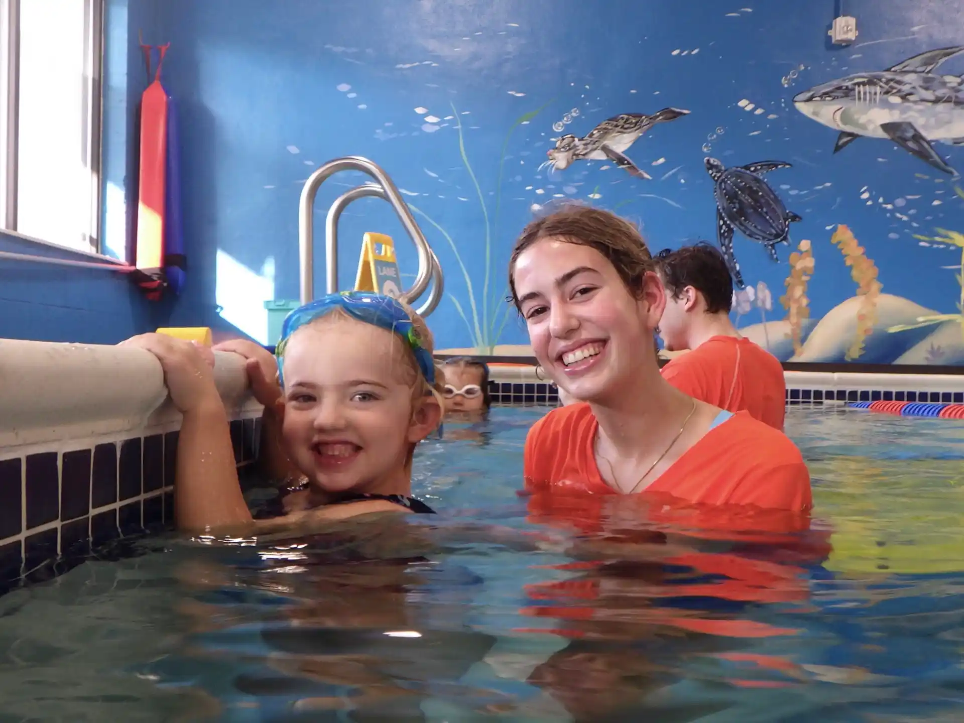 a man and a woman in a pool with fish in the background