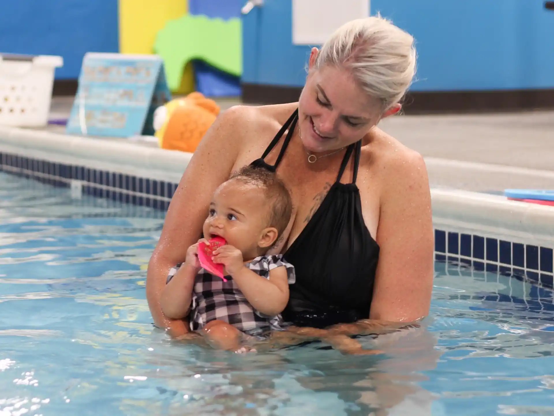a woman holding a baby in a pool