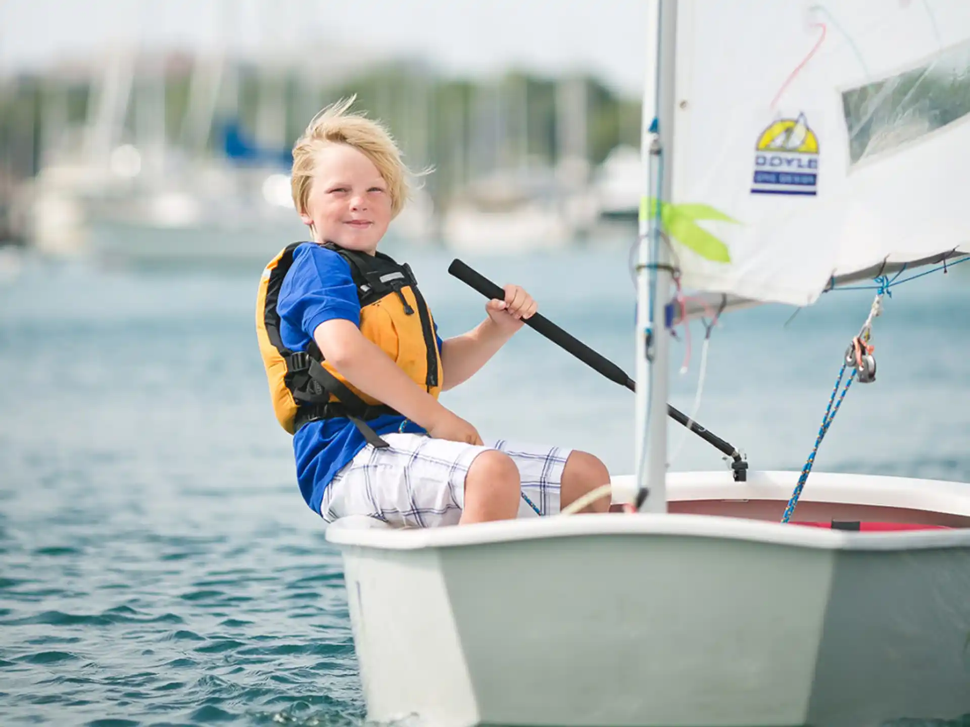 a girl in a life jacket on a sailboat