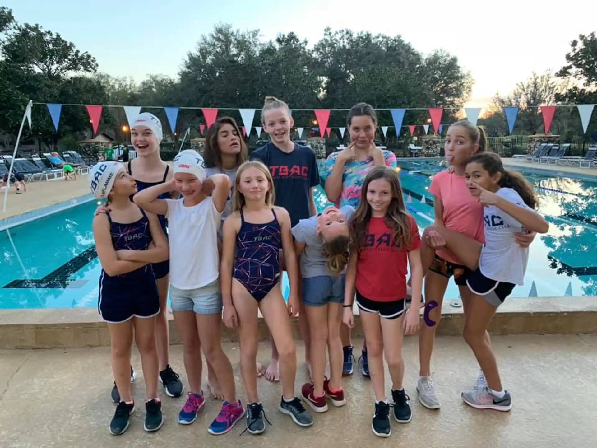 a group of people posing for a photo next to a pool
