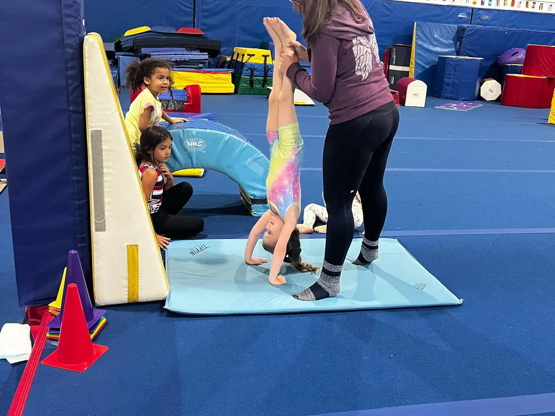 a woman and a child playing on a mat in a gym
