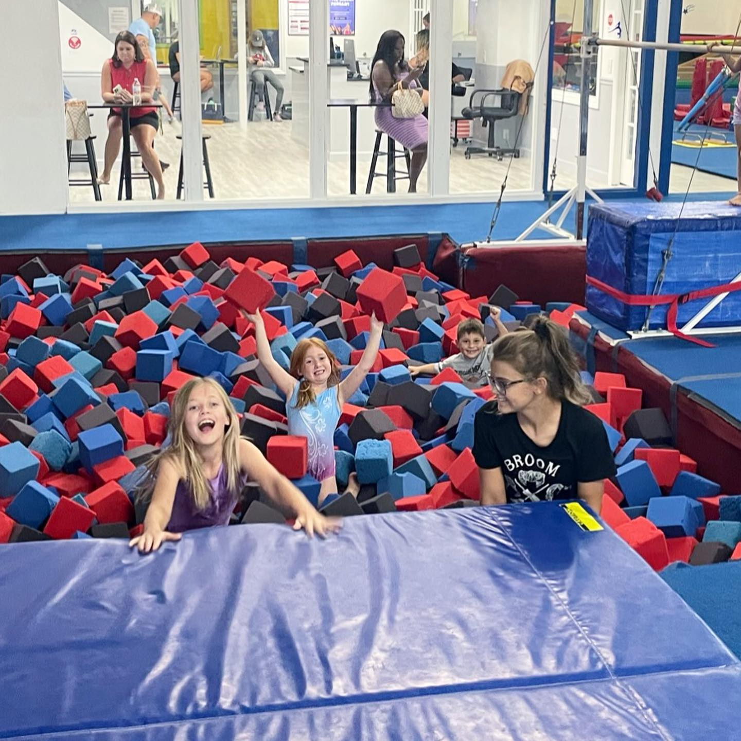 a group of people sitting on a blue mat in a gym