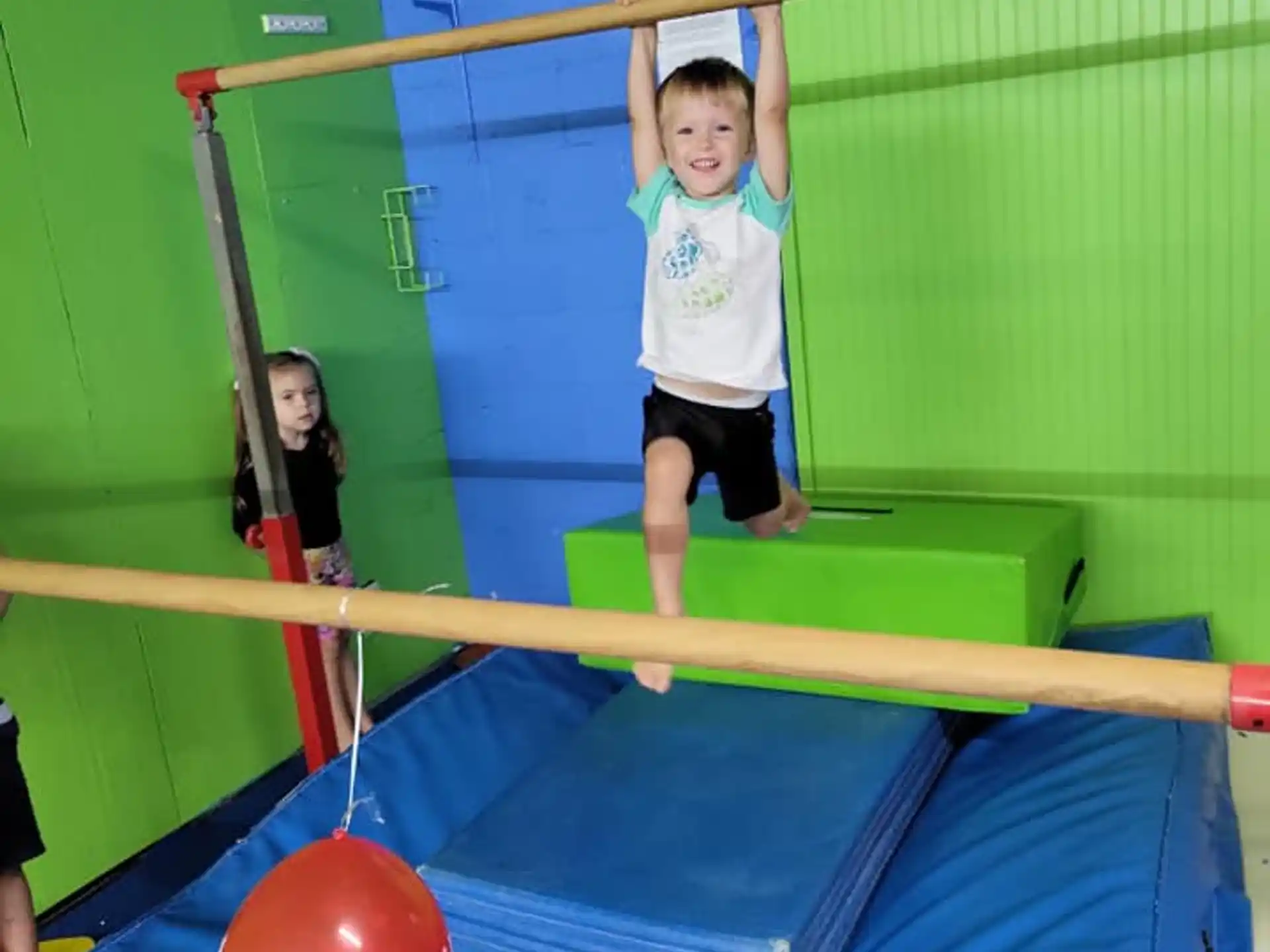 a boy standing on a trampoline with a ball and a girl in the background