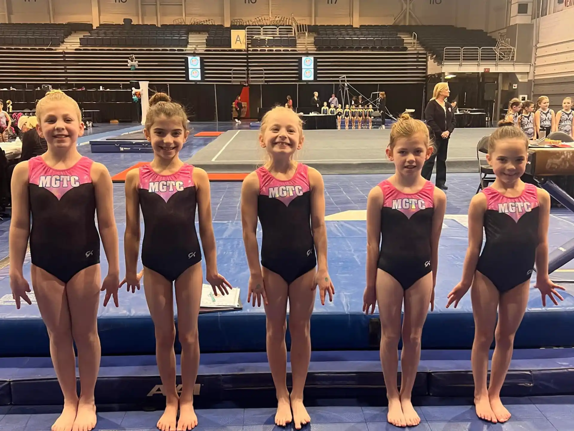 a group of women in leotards on a blue mat