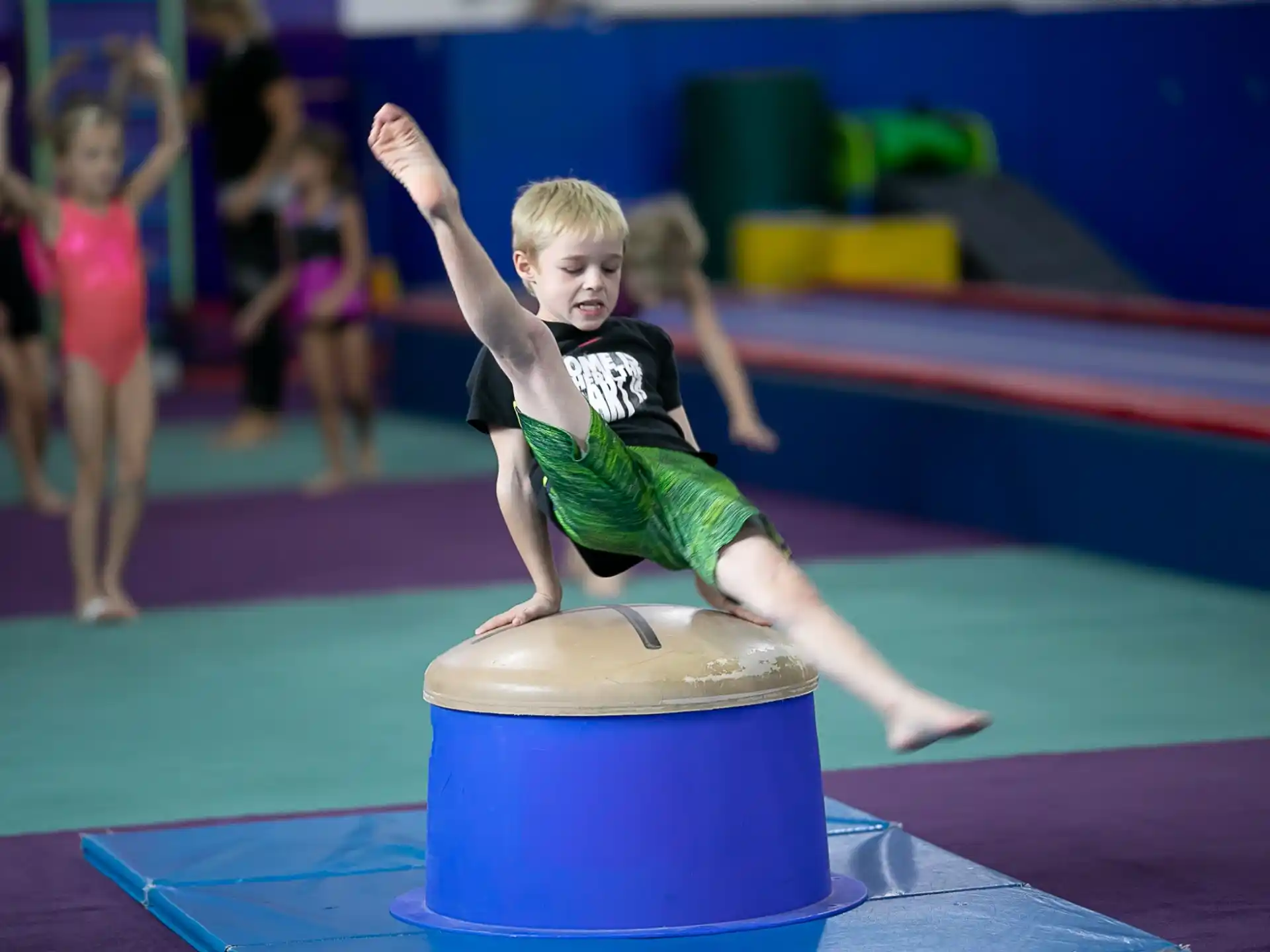 a boy jumping on a blue mat