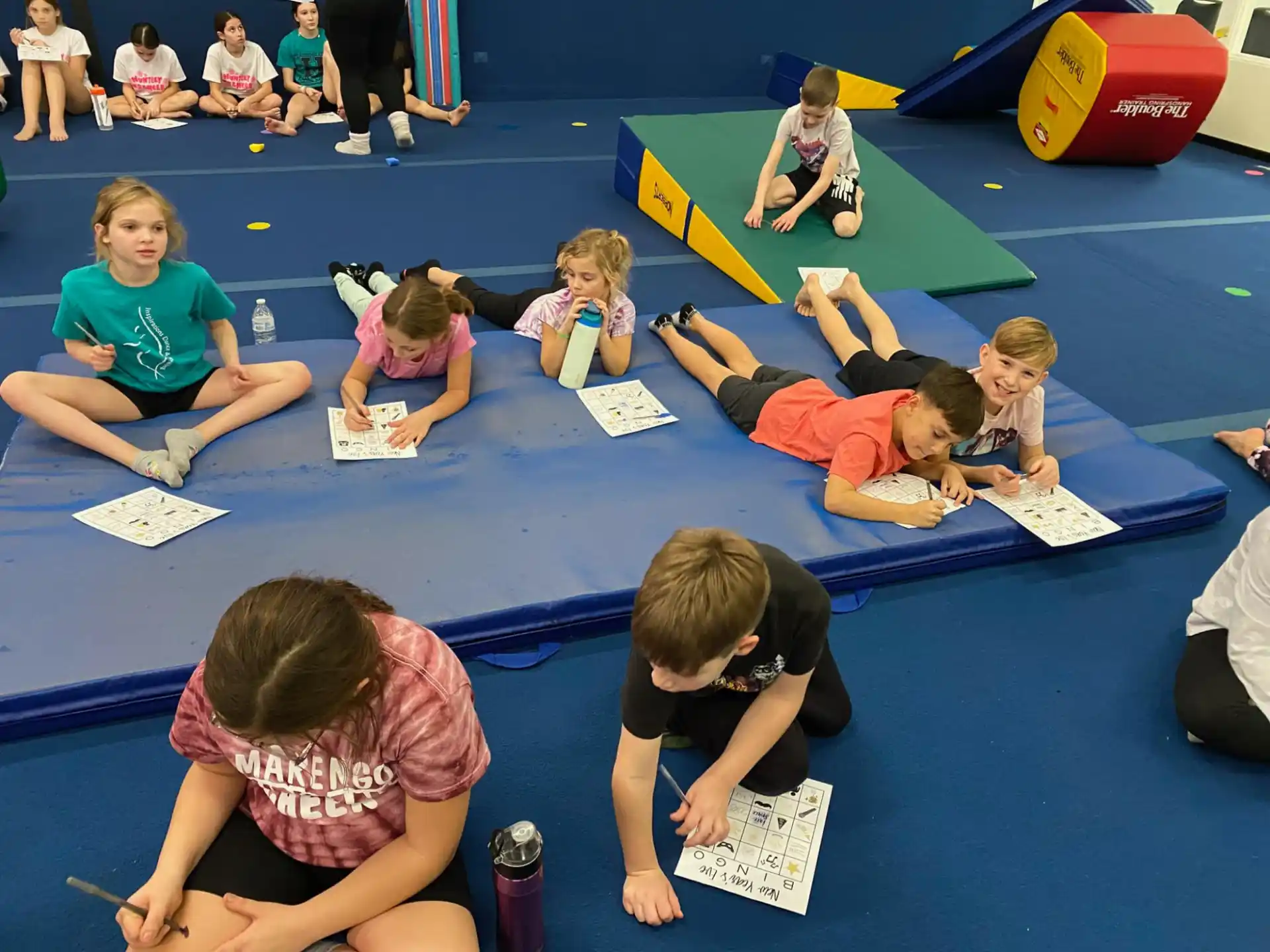 a group of children sitting on the floor writing on paper