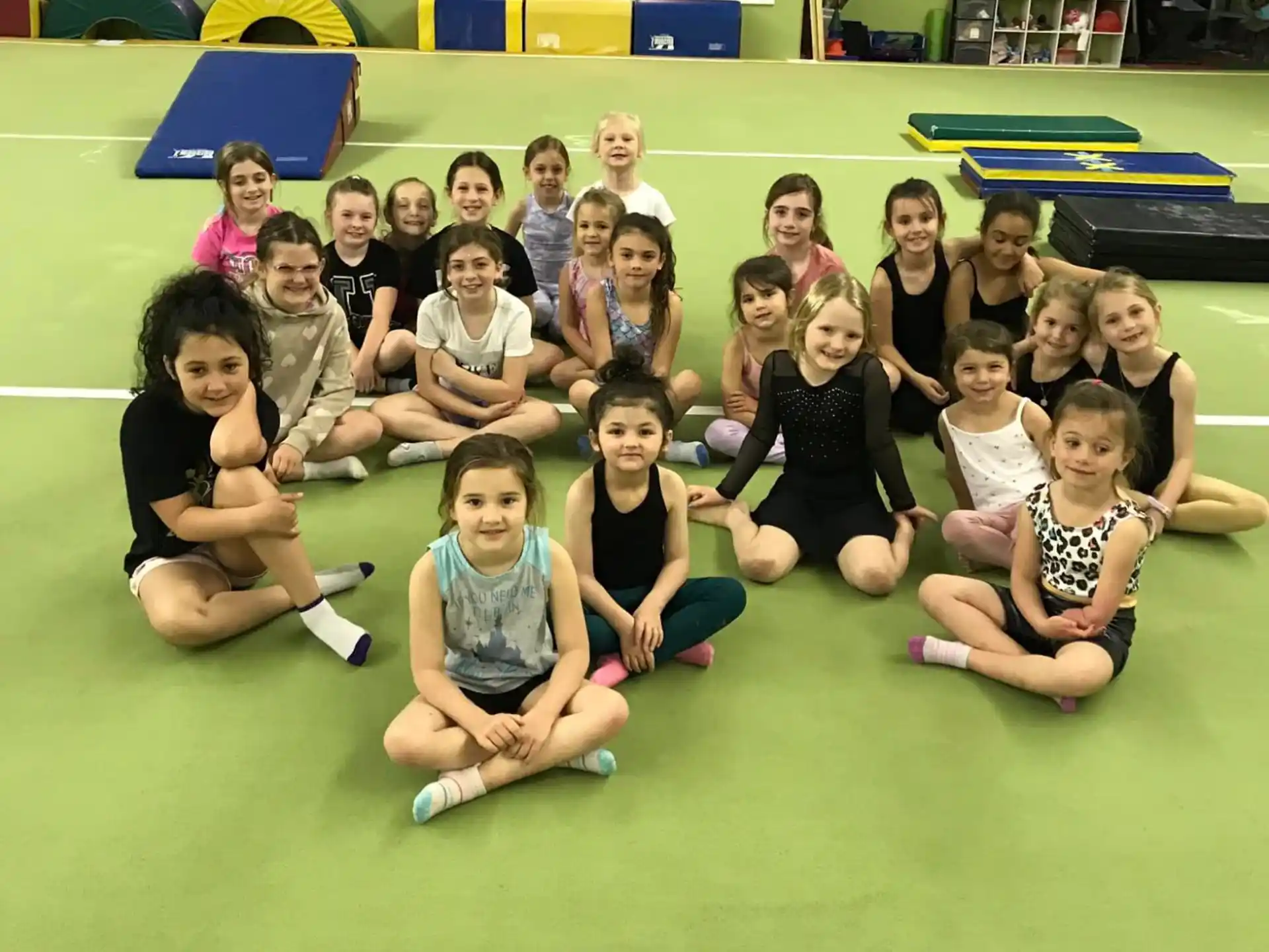 a group of children sitting on the floor posing for a photo