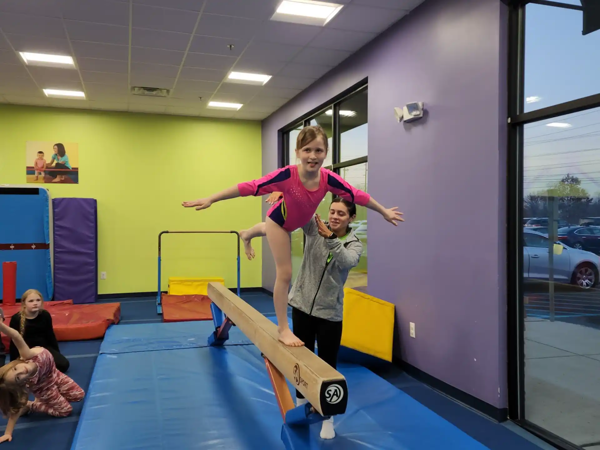 a person standing on a mat in a room with children and a window