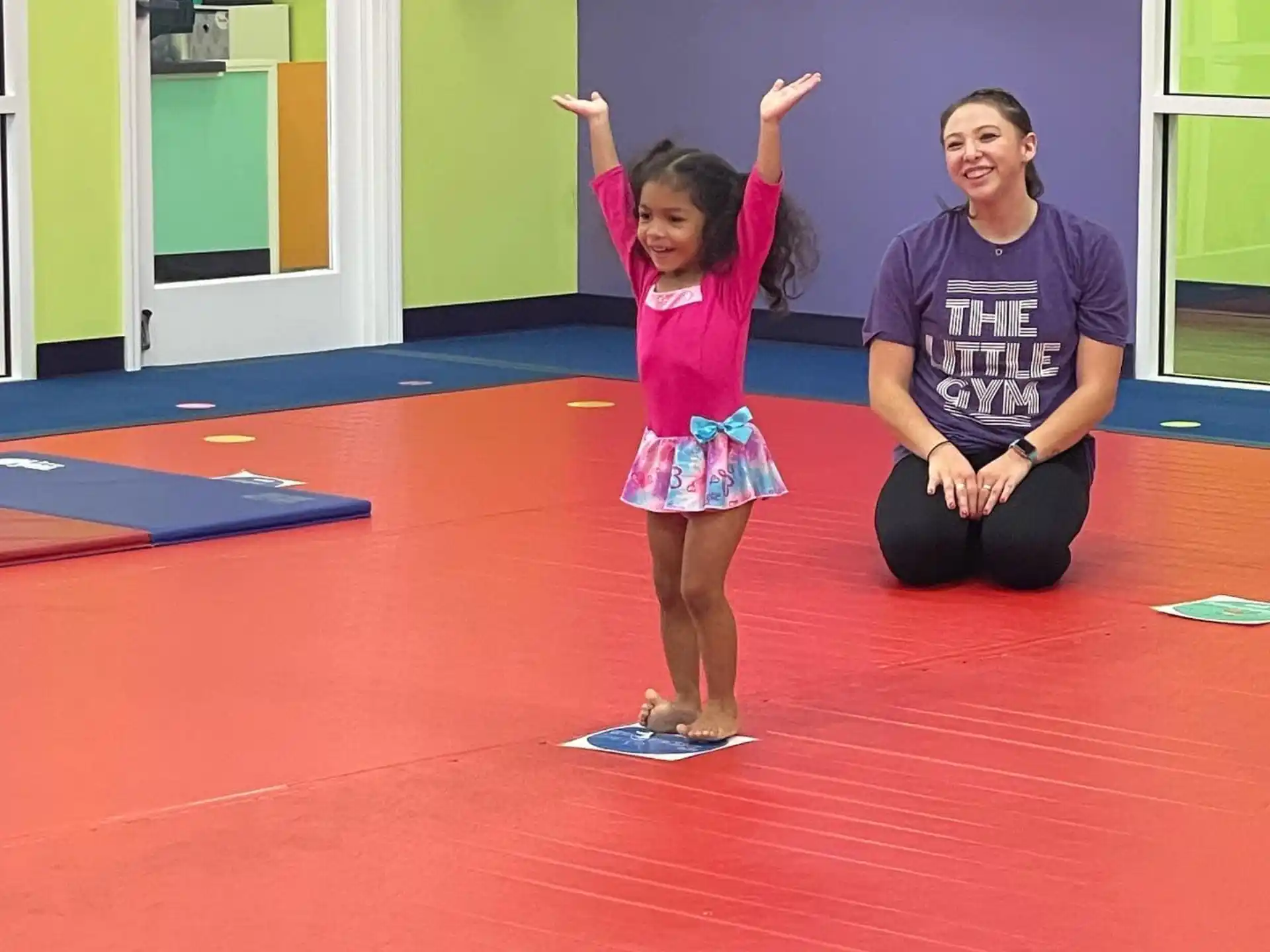 a girl standing on a mat with her arms up