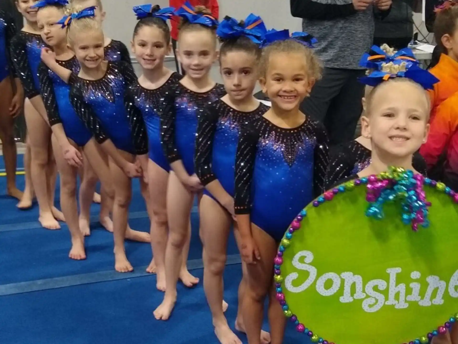 a group of girls in blue and black uniforms holding a green balloon