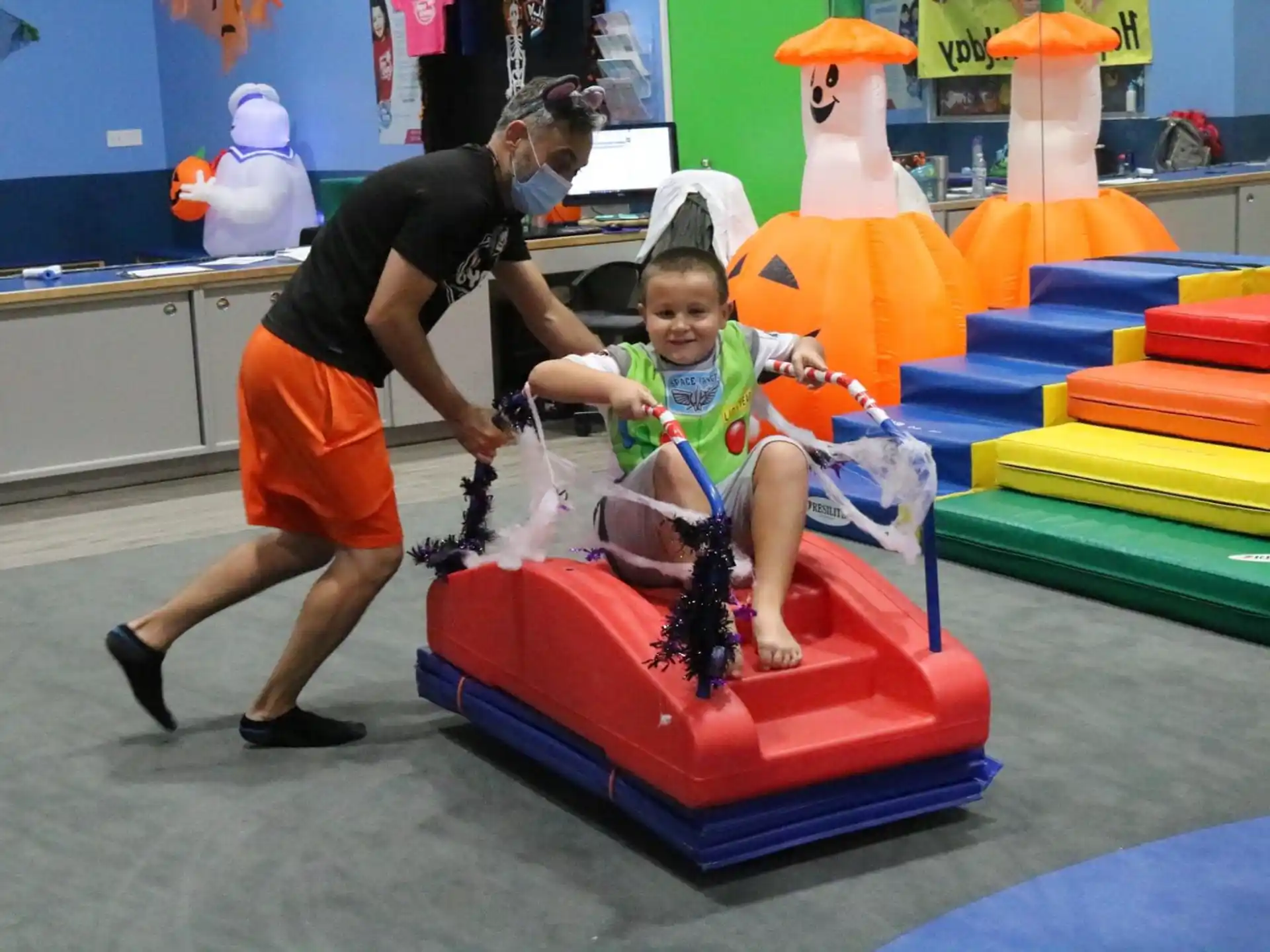 a person and a child playing on a toy in a room