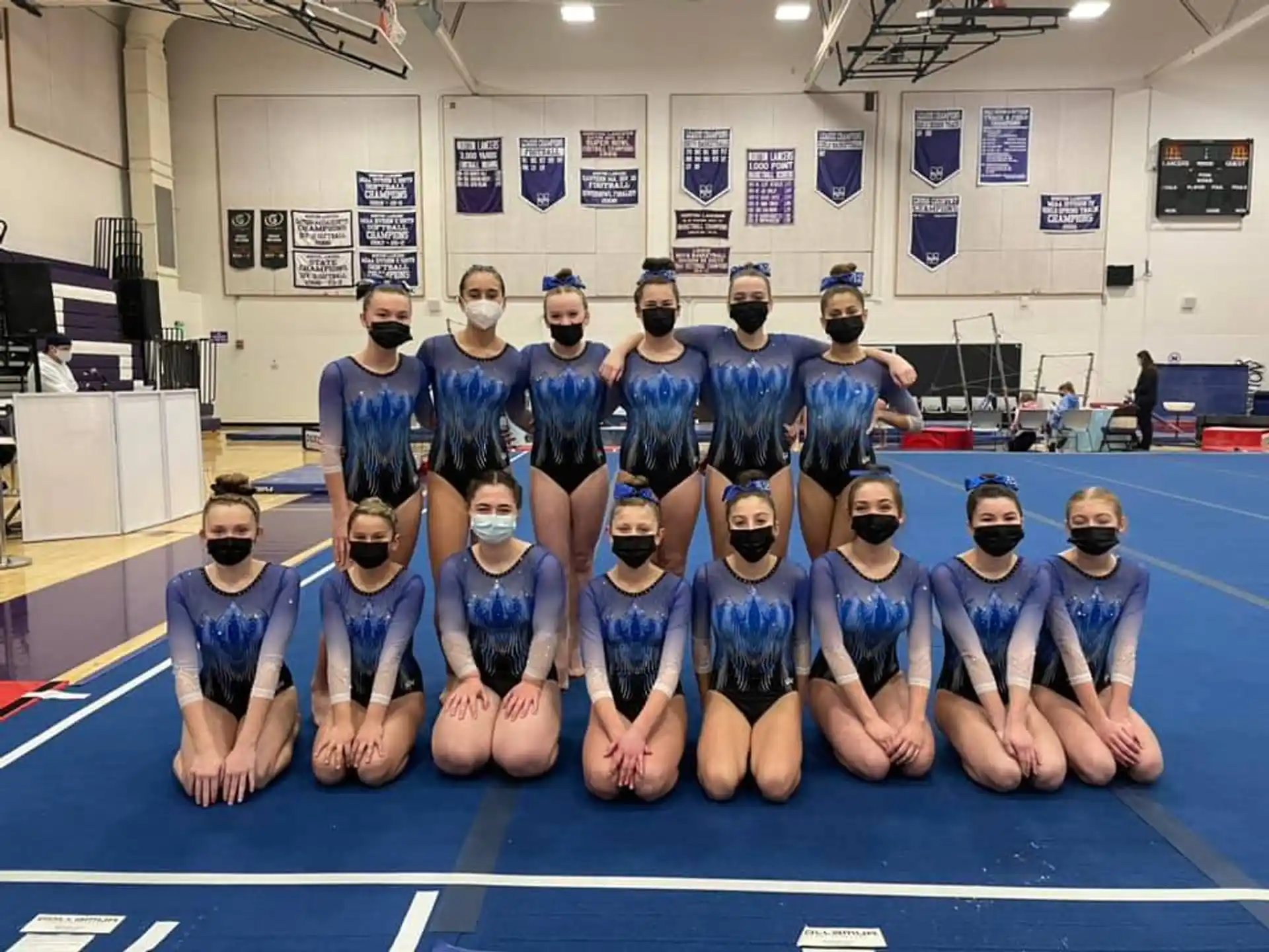 a group of people wearing blue shirts and masks posing for a photo