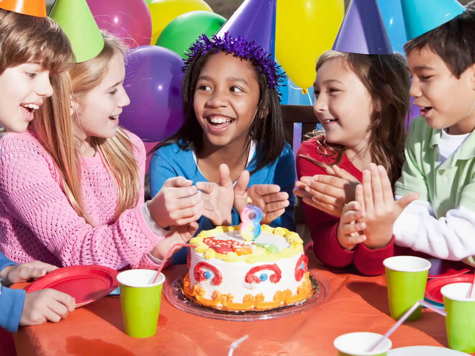 a group of children around a birthday cake