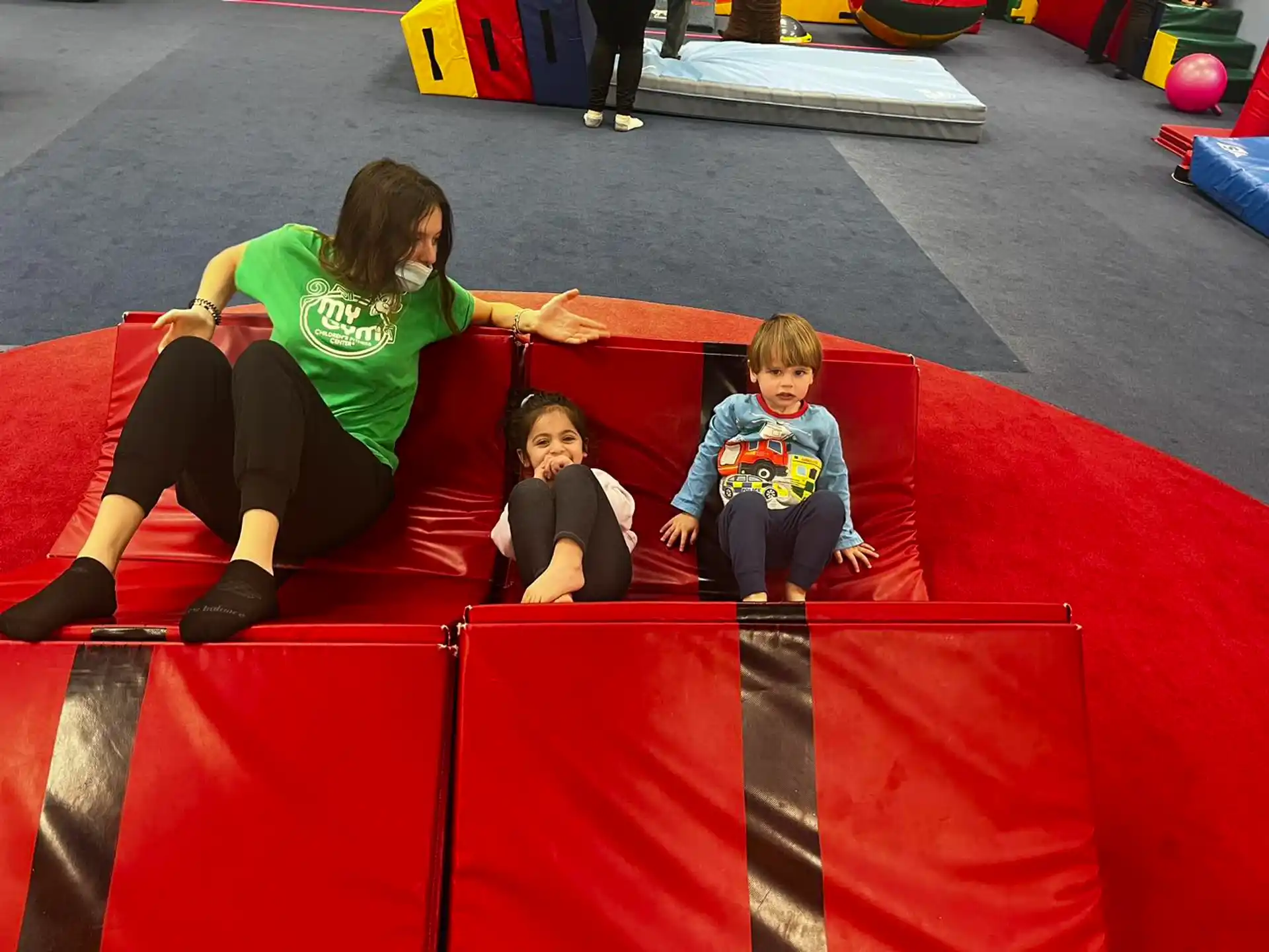 a person and two children on a red and yellow mat