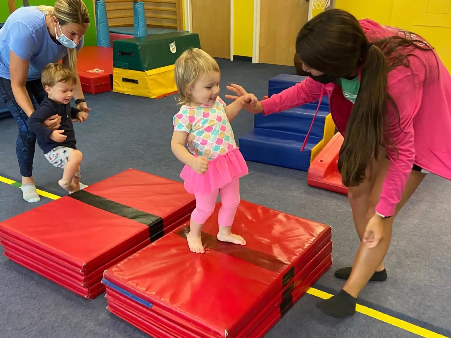 a person and children playing on a mat in a gym