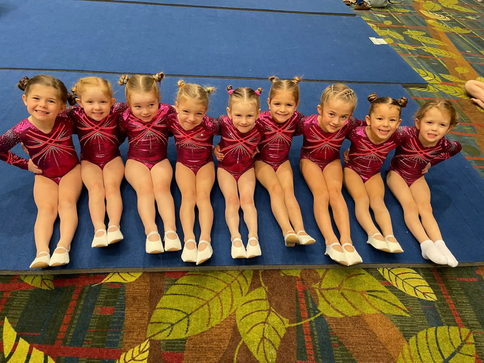 a group of girls in red and white uniforms sitting on a mat
