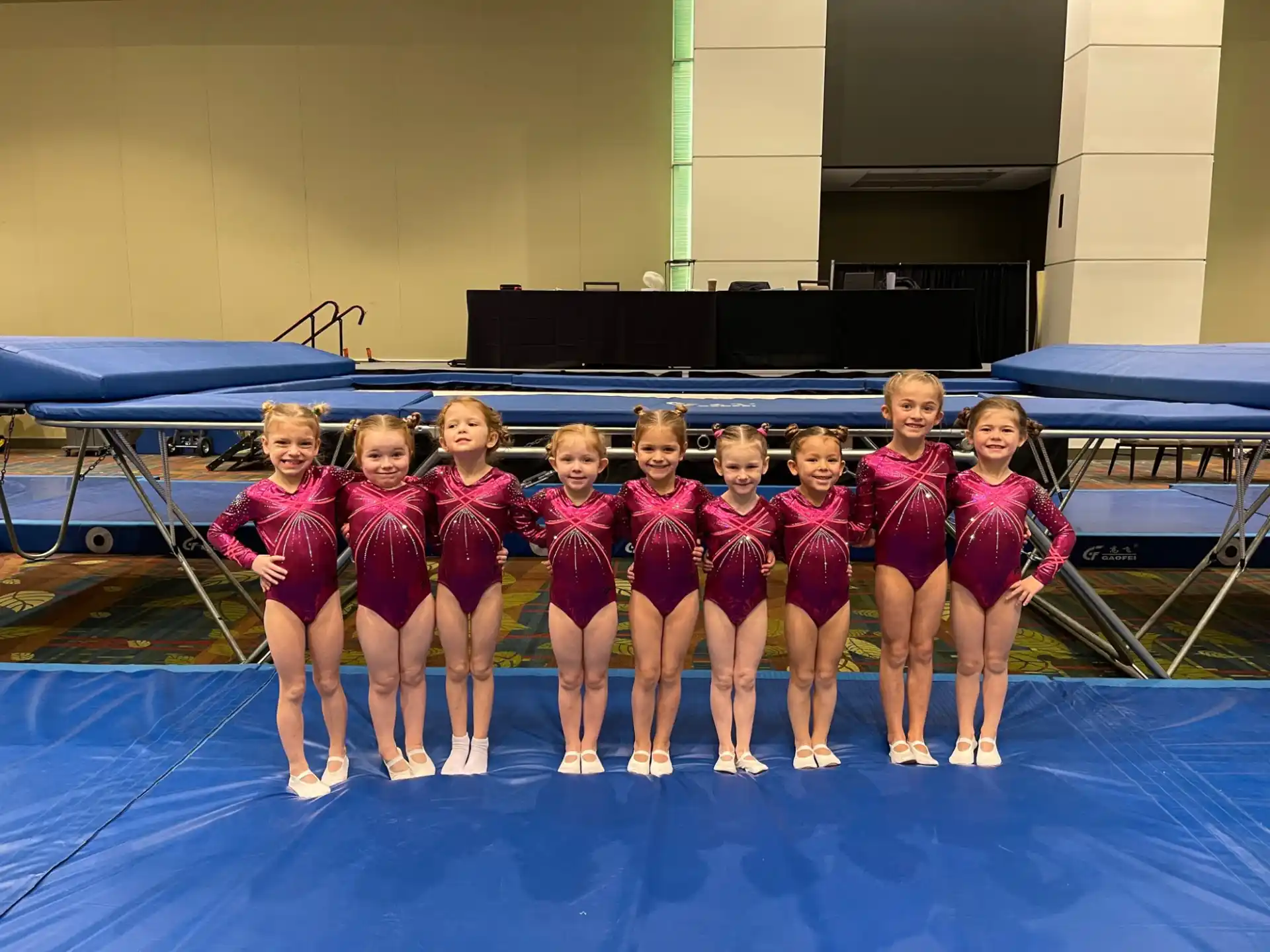 a group of girls in red and white uniforms standing on a blue mat