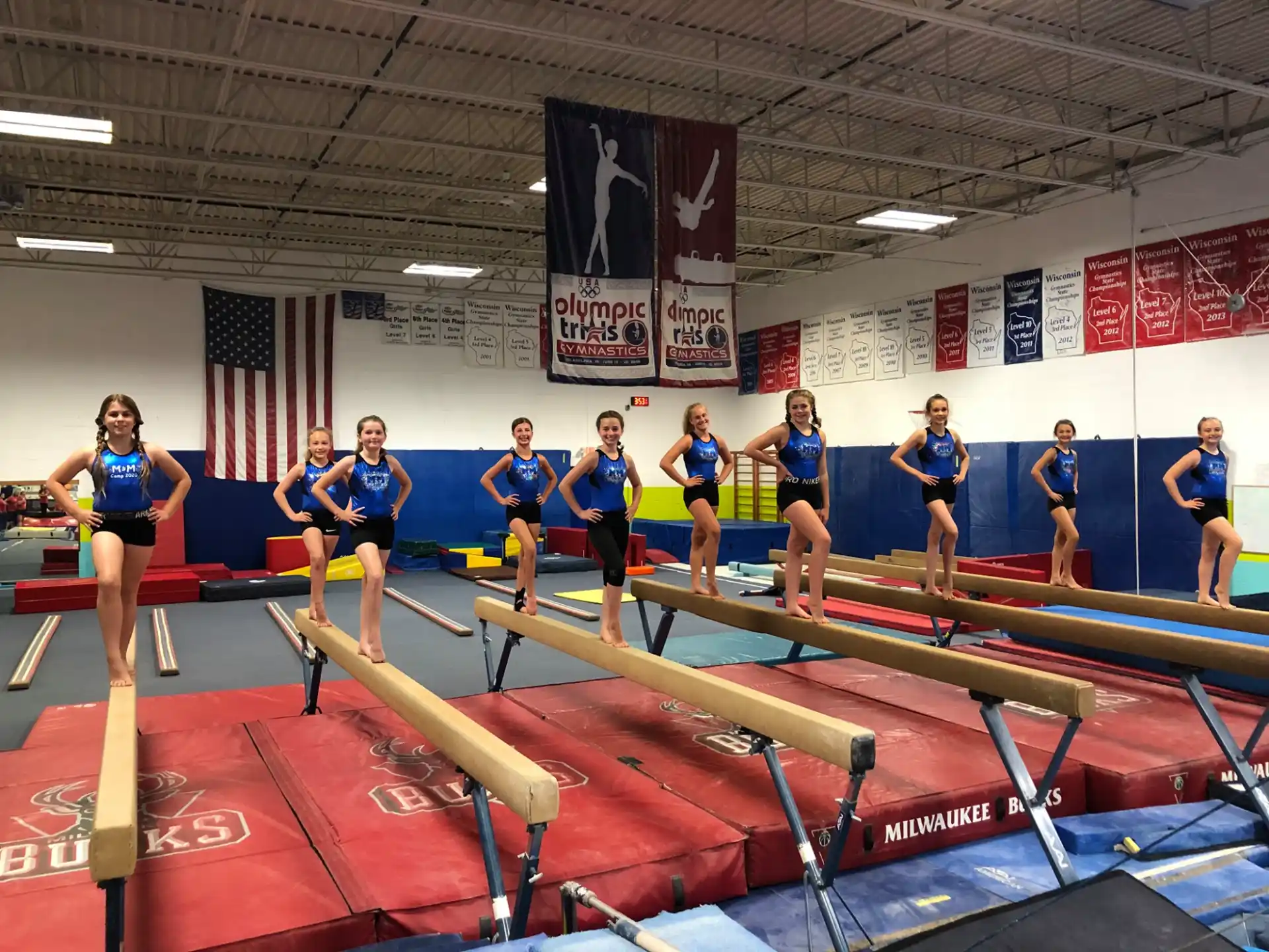 a group of women in blue shirts standing on a mat in a gym