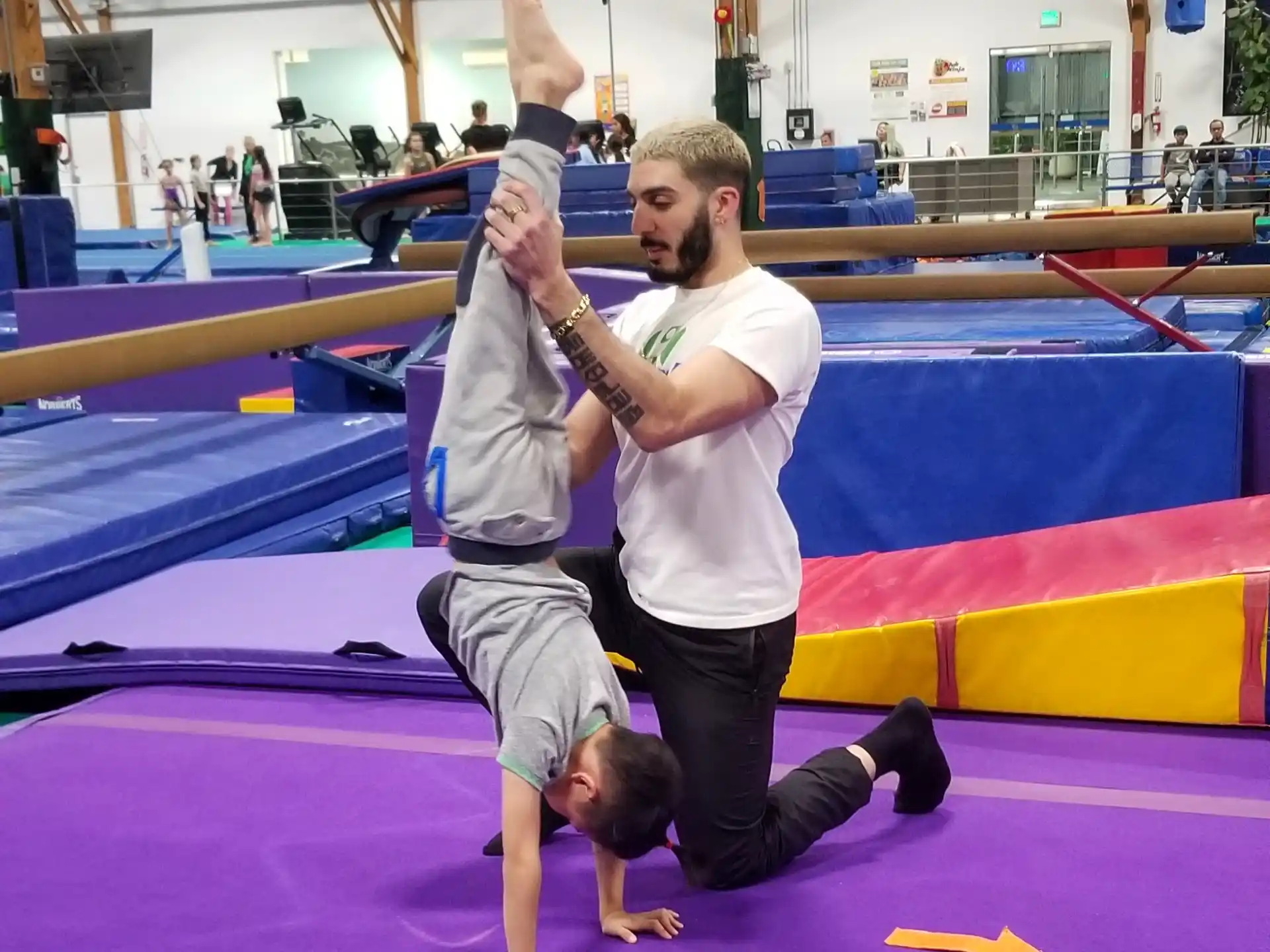 a person holding another man on the back in a gym