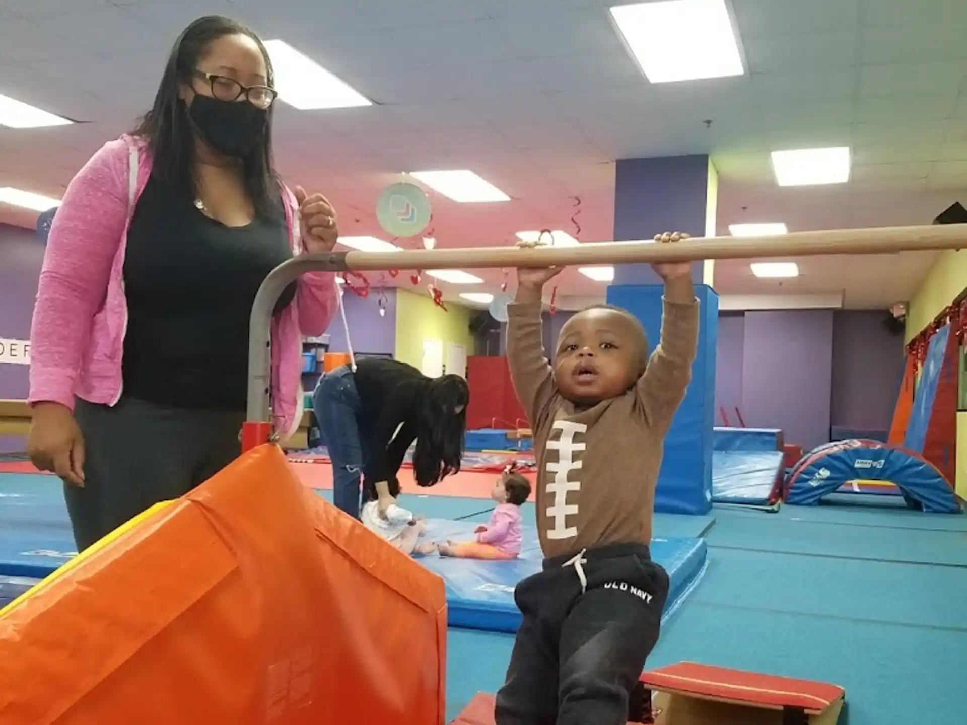 a woman and a child on a slide in a room with other people