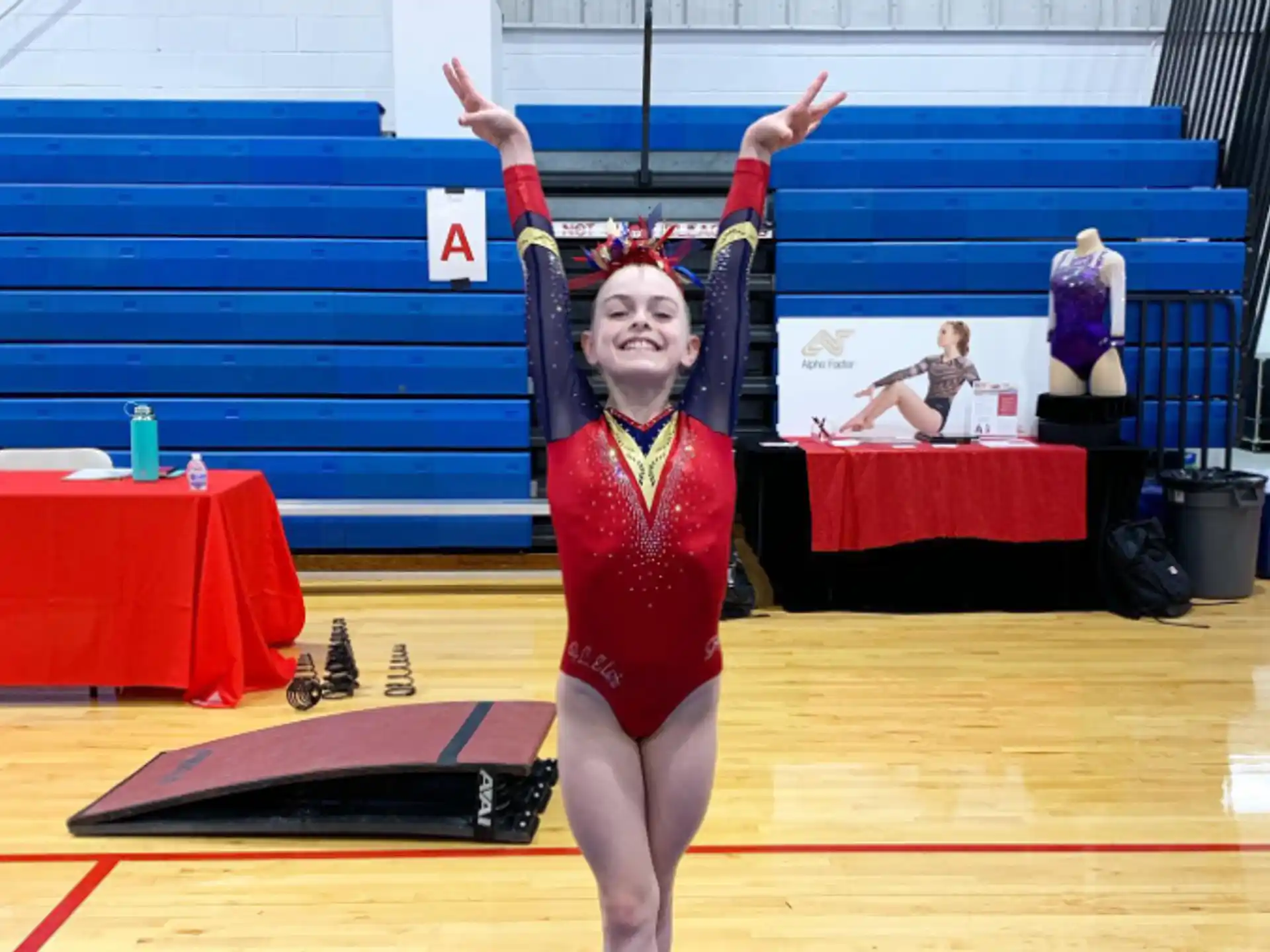 a woman in a leotard on a mat with her arms up