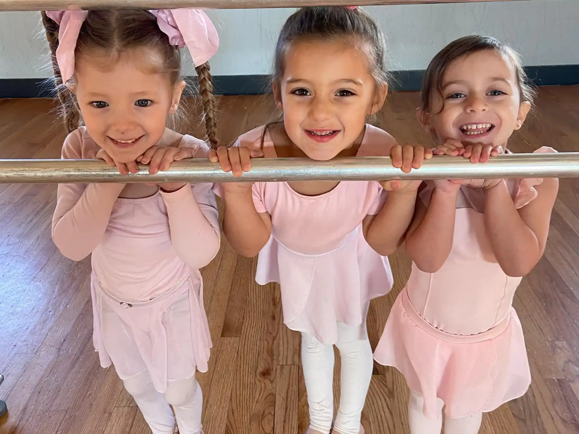 a group of girls wearing white dresses and holding a white bar