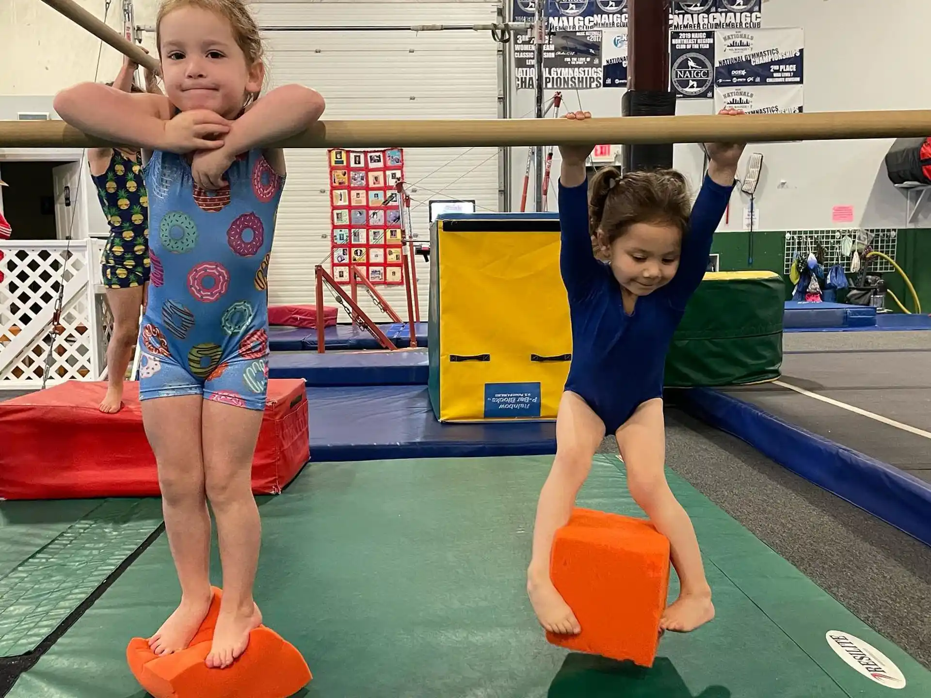 a couple of kids playing on a mat in a gym