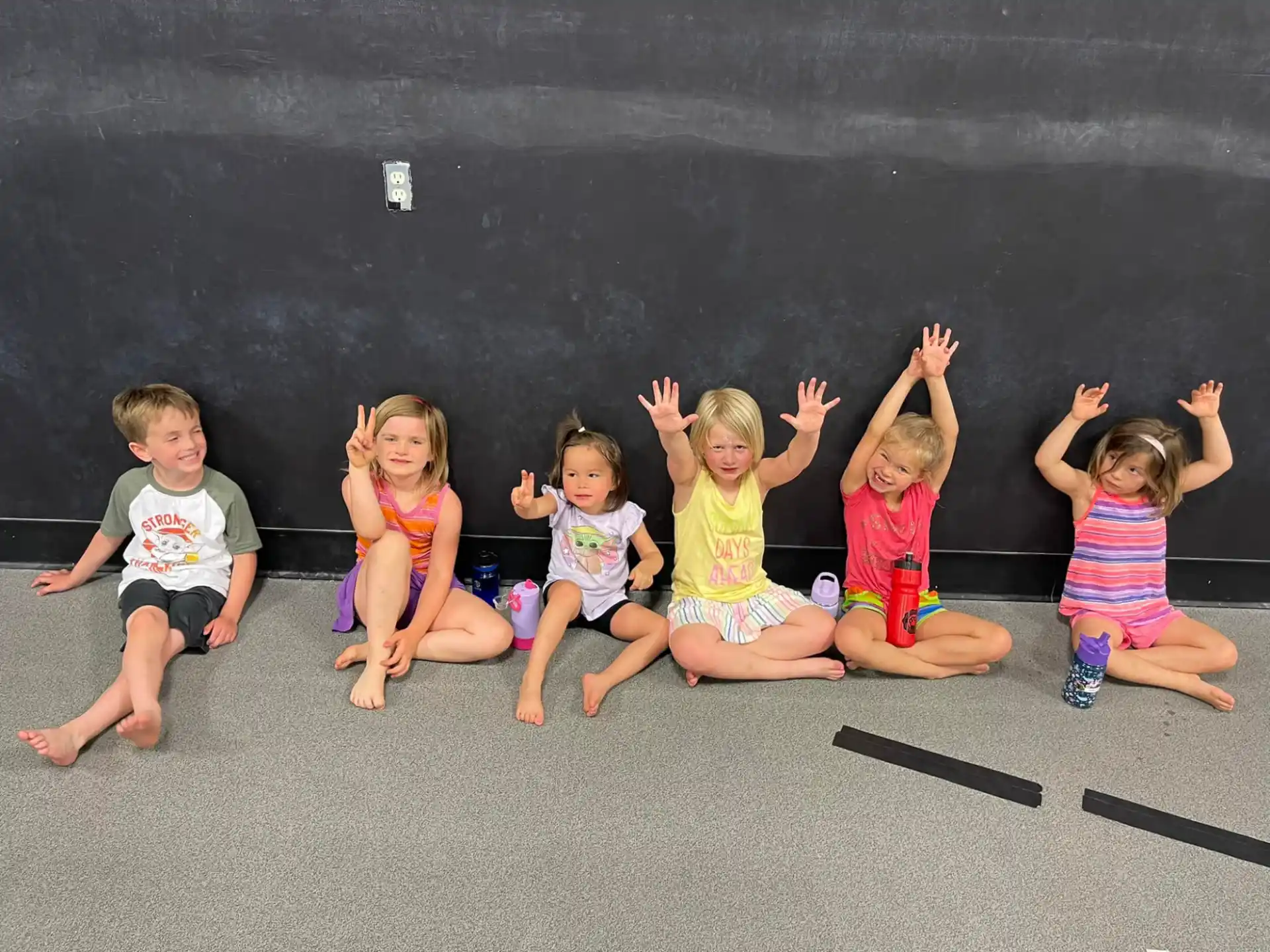 a group of children sitting on the ground with their arms up