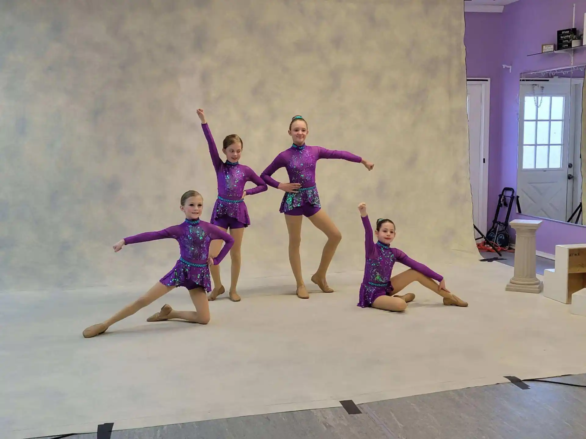 a group of girls in purple dresses jumping in the air