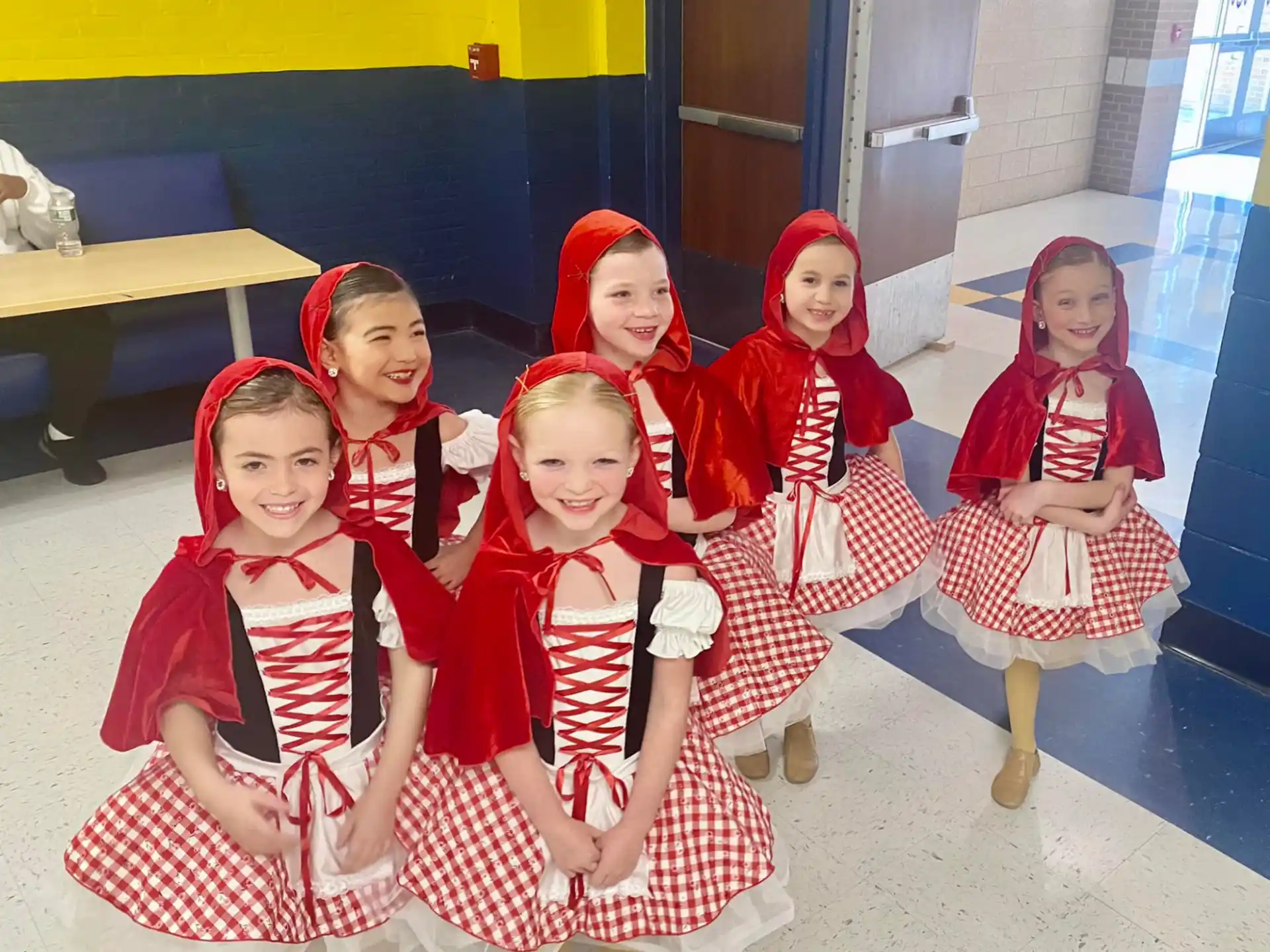 a group of girls in red and white dresses sitting on a bench